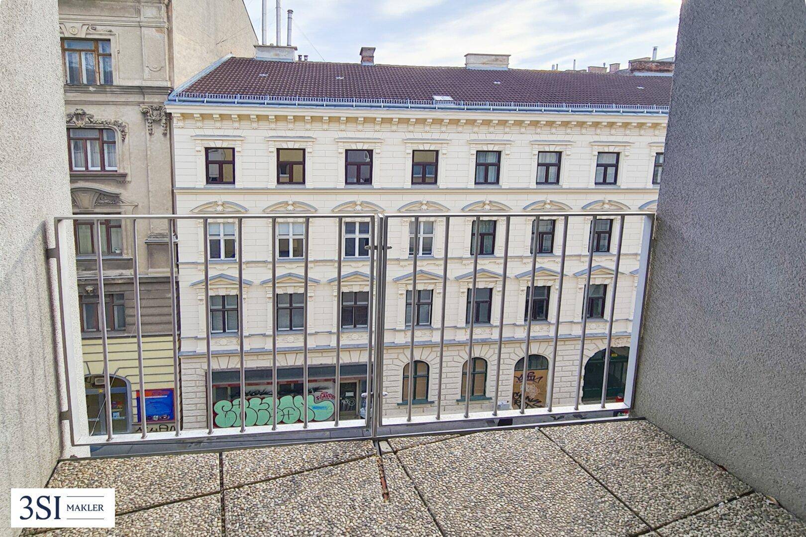 Blick vom Balkon auf die gegenüberliegende historische Fassade eines Gebäudes in der Stadt.