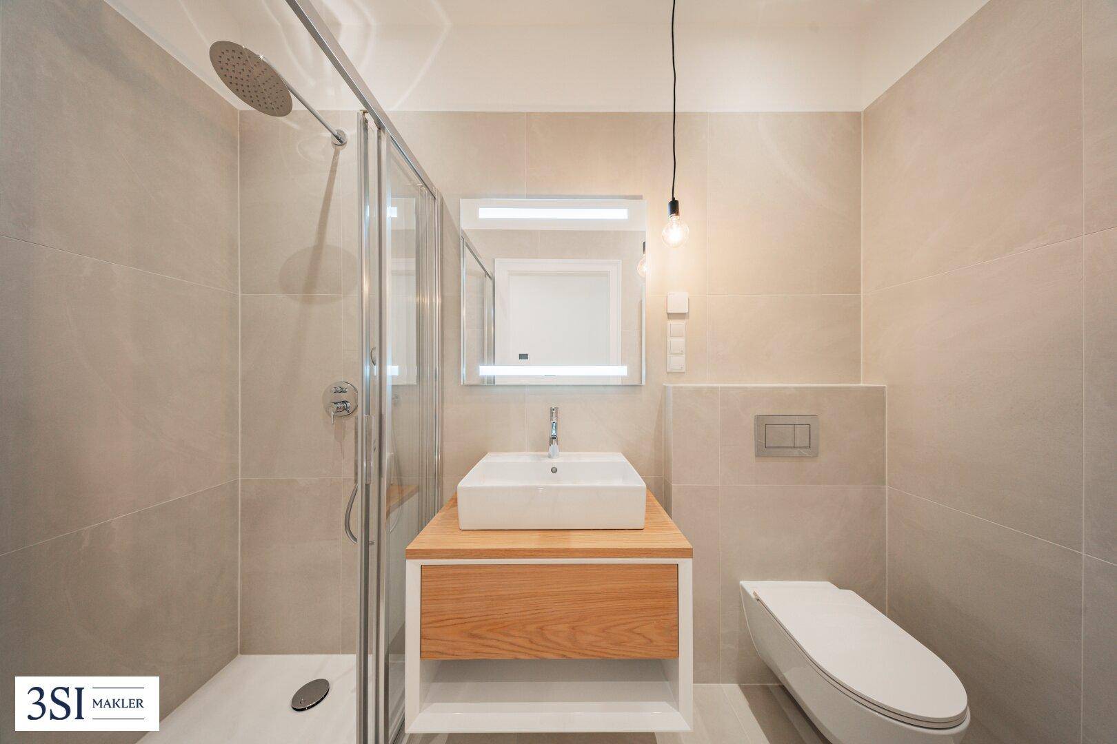 Helles Badezimmer mit moderner Dusche, Waschtisch und wandhängendem WC.