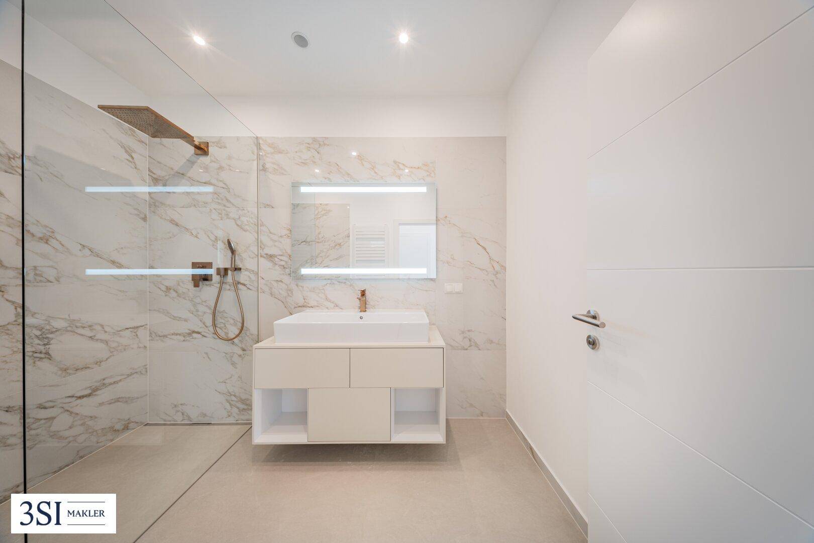 Elegantes Badezimmer mit Marmorfliesen, modernem Waschtisch und großer, ebenerdiger Dusche.