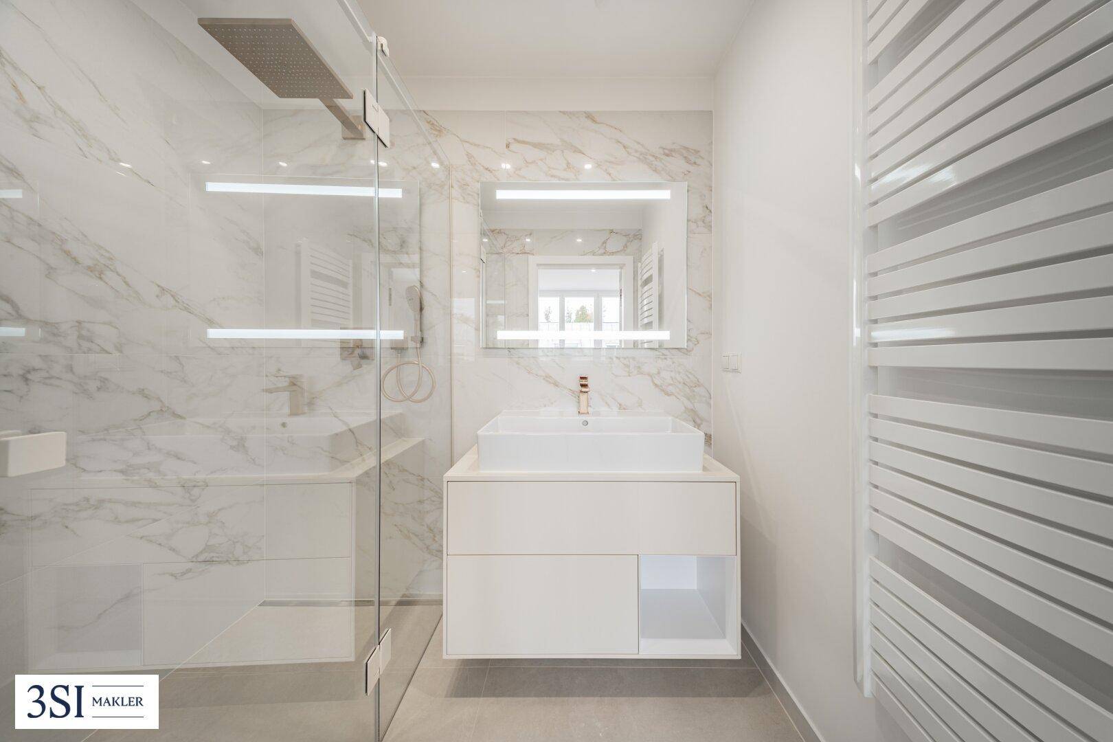Modernes Badezimmer mit Marmorfliesen, begehbarer Dusche, Einzelwaschbecken und beheiztem Handtuchhalter.
