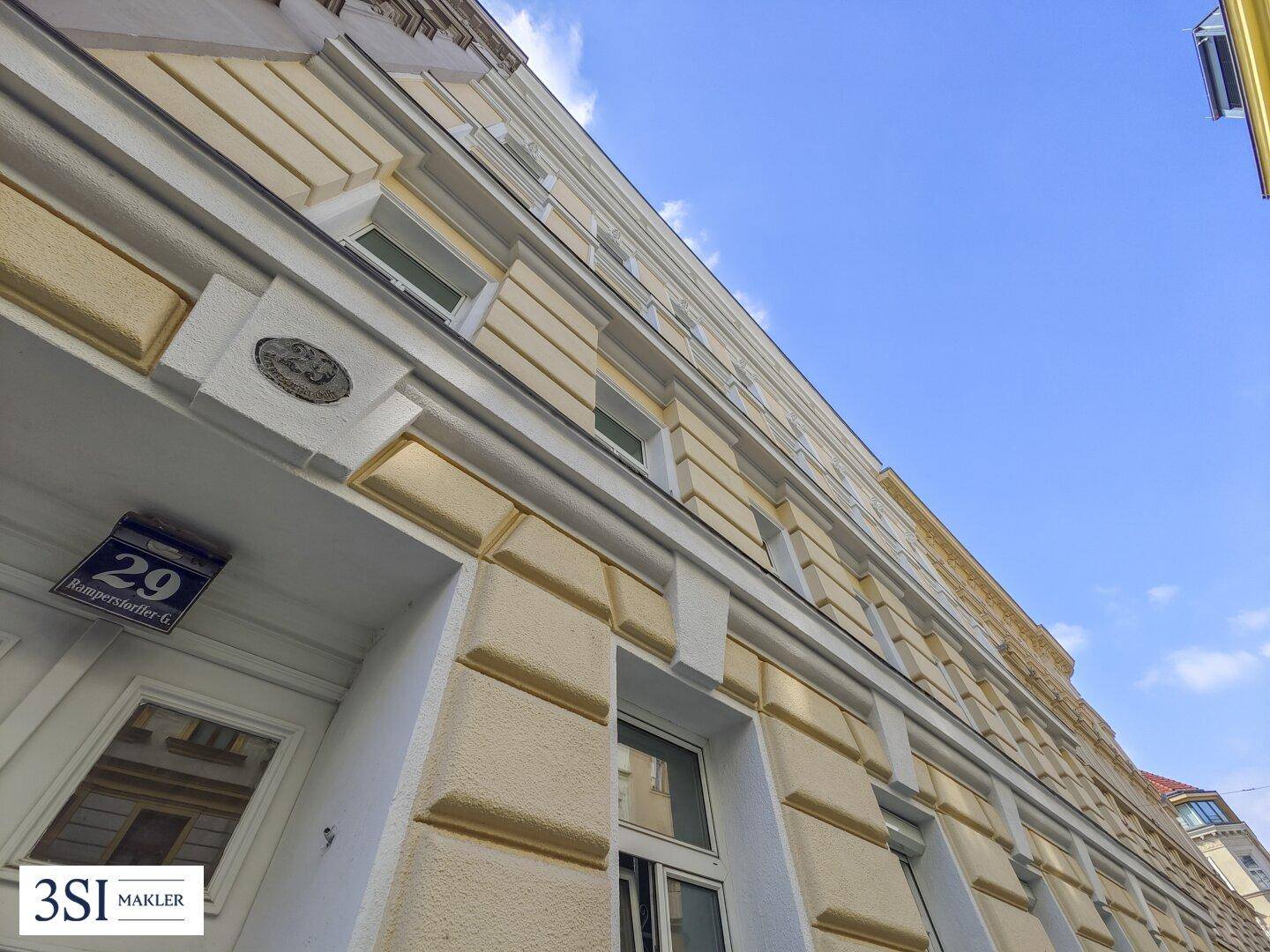 Blick auf die historische Fassade eines Altbaus mit dekorativen Elementen und blauer Himmel.