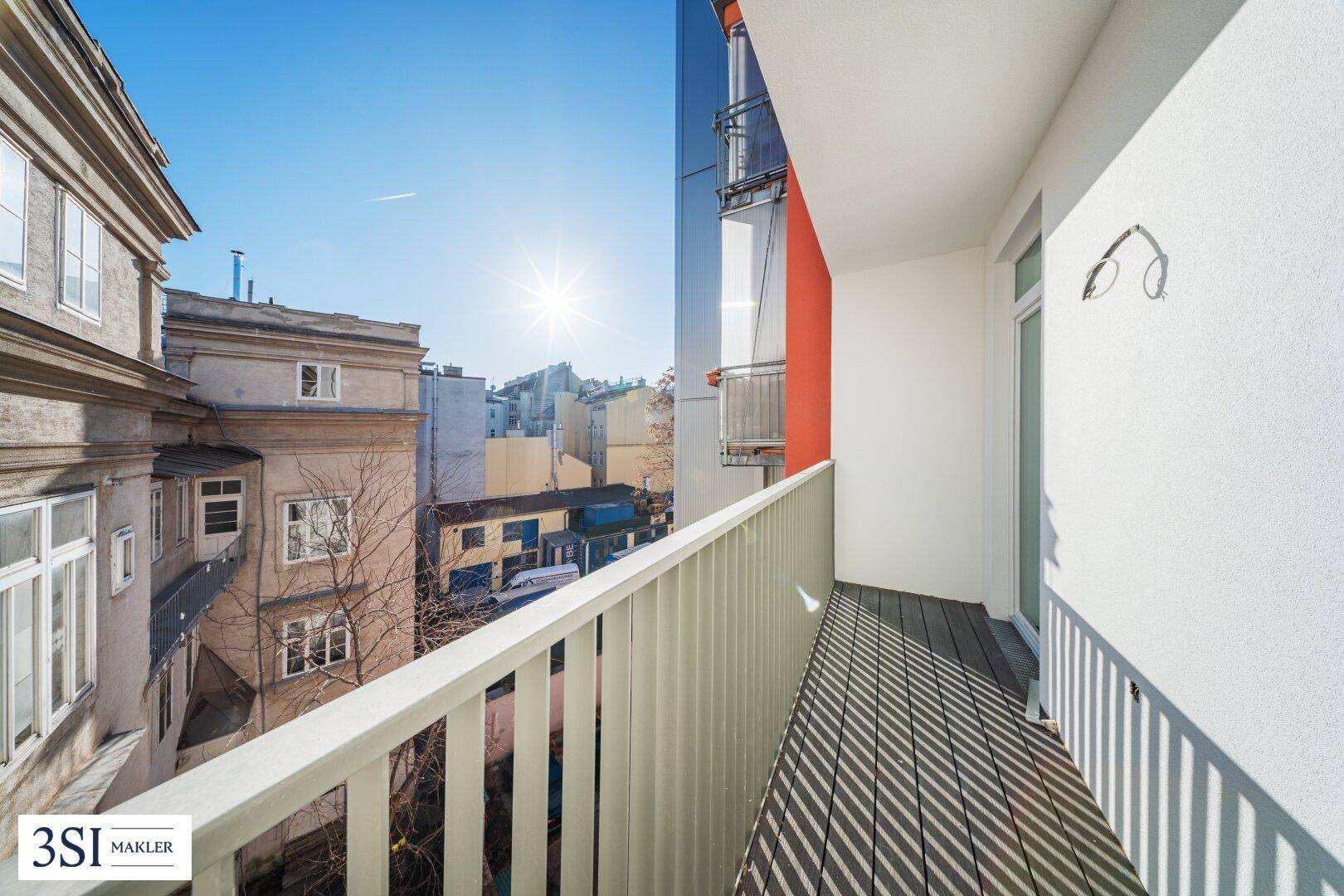 Sonniger Balkon mit Holzboden und Blick auf die umliegenden Stadtgebäude, ideal zum Entspannen.