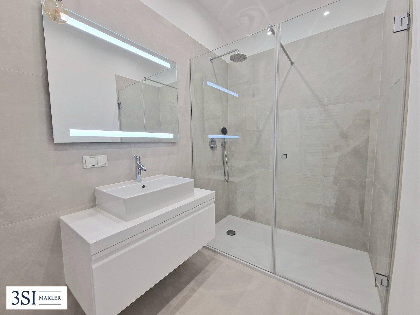Modernes Badezimmer mit großformatigen Fliesen, Einzelwaschbecken und geräumiger Duschkabine.