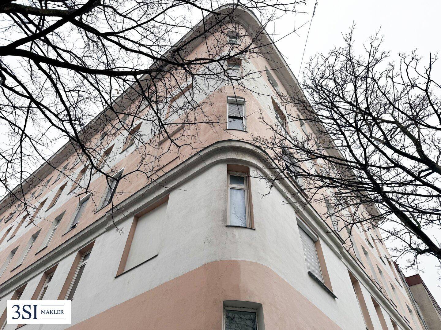 Eindrucksvolle Eckansicht eines Altbaus mit abgerundeten Formen und vielen Fenstern.