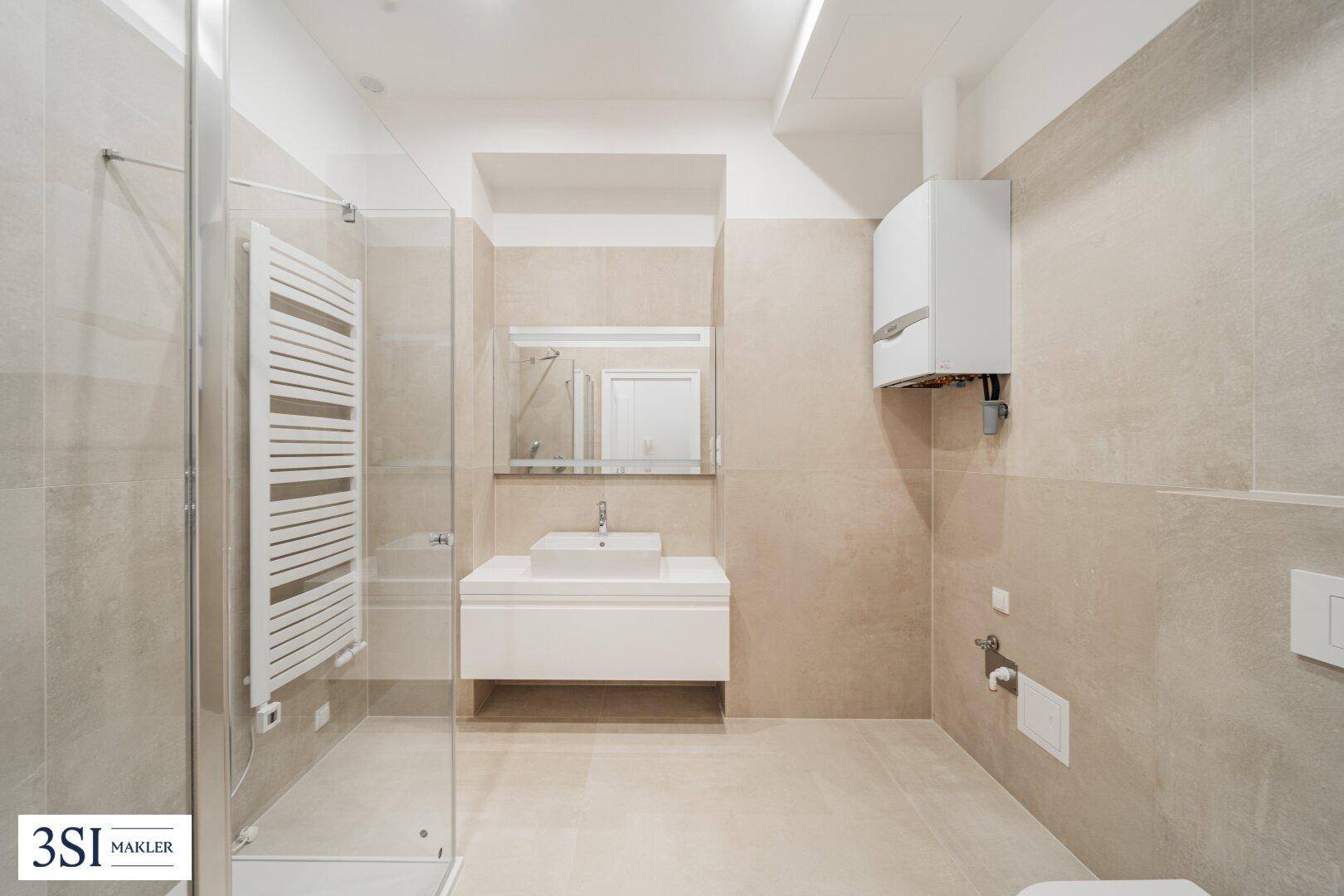 Modernes Badezimmer mit beigefarbenen Fliesen, ebenerdiger Dusche und beheiztem Handtuchhalter.