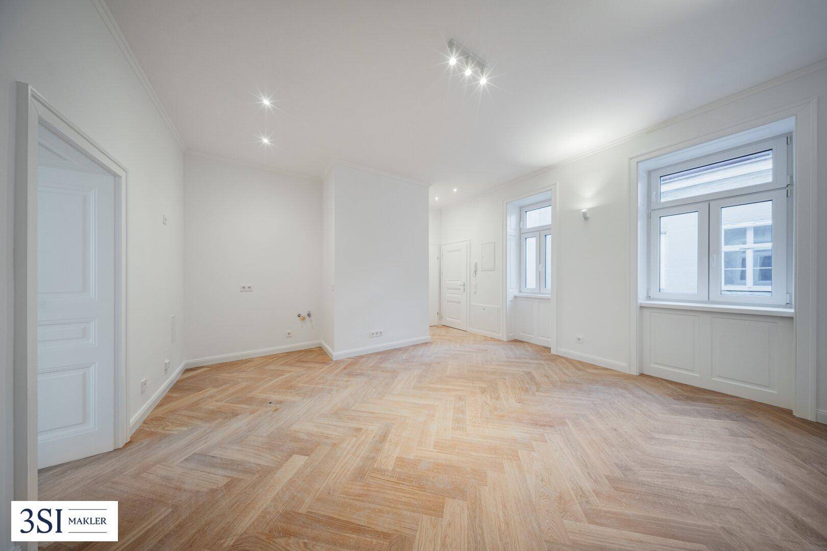 Helles, leeres Zimmer mit Fischgrätparkett und weißen Wänden, bereit zur individuellen Gestaltung.