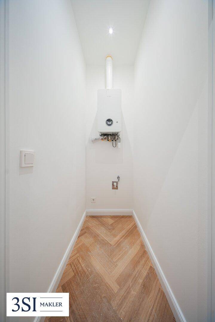 Schmaler Raum mit Gastherme und Fischgrätparkett, ideal als Abstell- oder Technikraum.