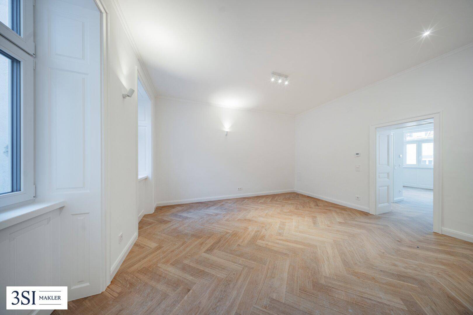 Geräumiges, helles Zimmer mit elegantem Fischgrätparkett und Blick auf die Umgebung.