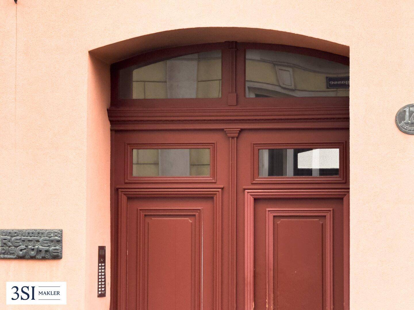 Detailaufnahme des klassischen Hauseingangs mit Holztür und Klingelanlage.