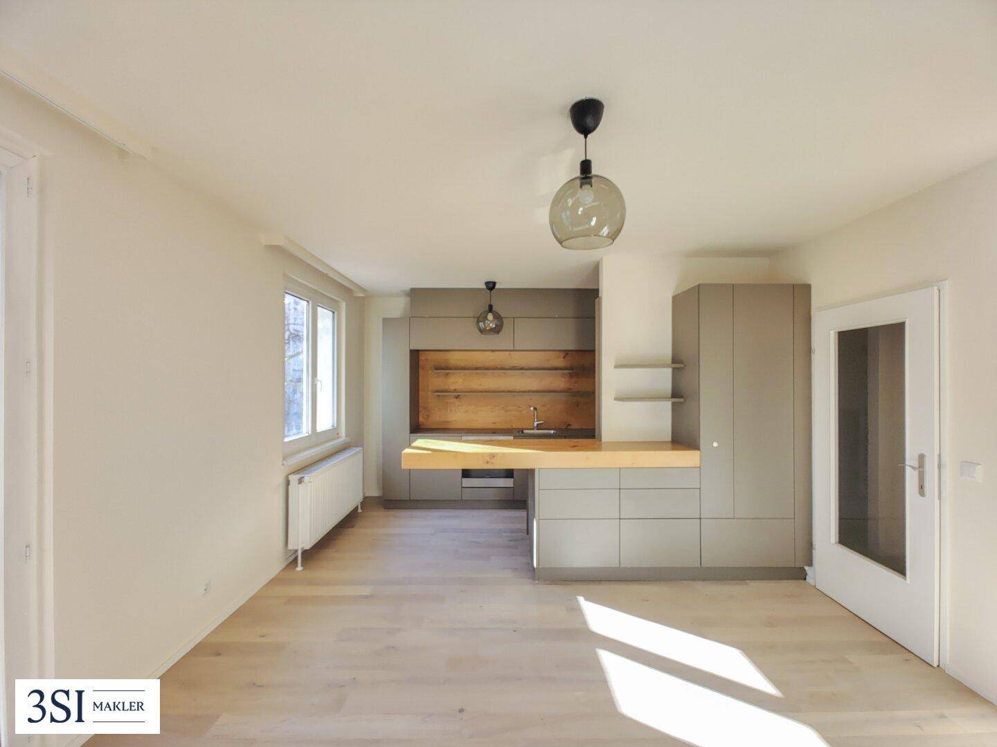 Moderne Einbauküche in hellem Raum mit Holztheke und viel Tageslicht.