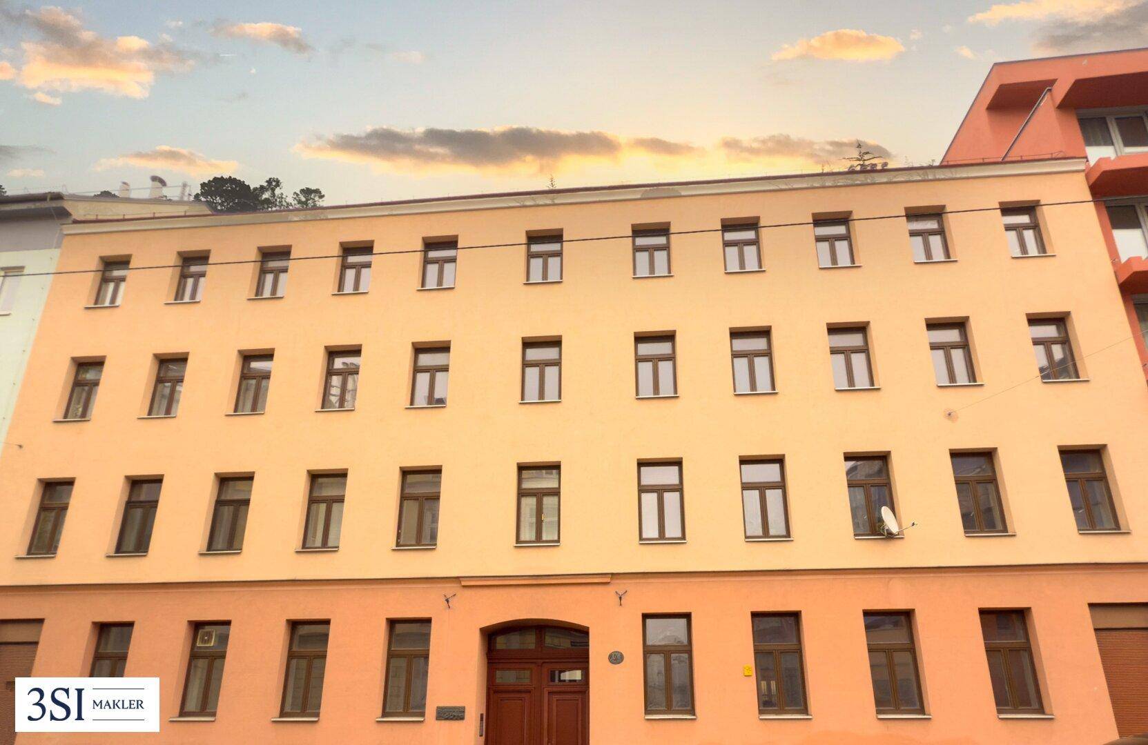 Gesamtansicht der Fassade eines Mehrfamilienhauses mit vielen Fenstern und einem warmen Farbton.