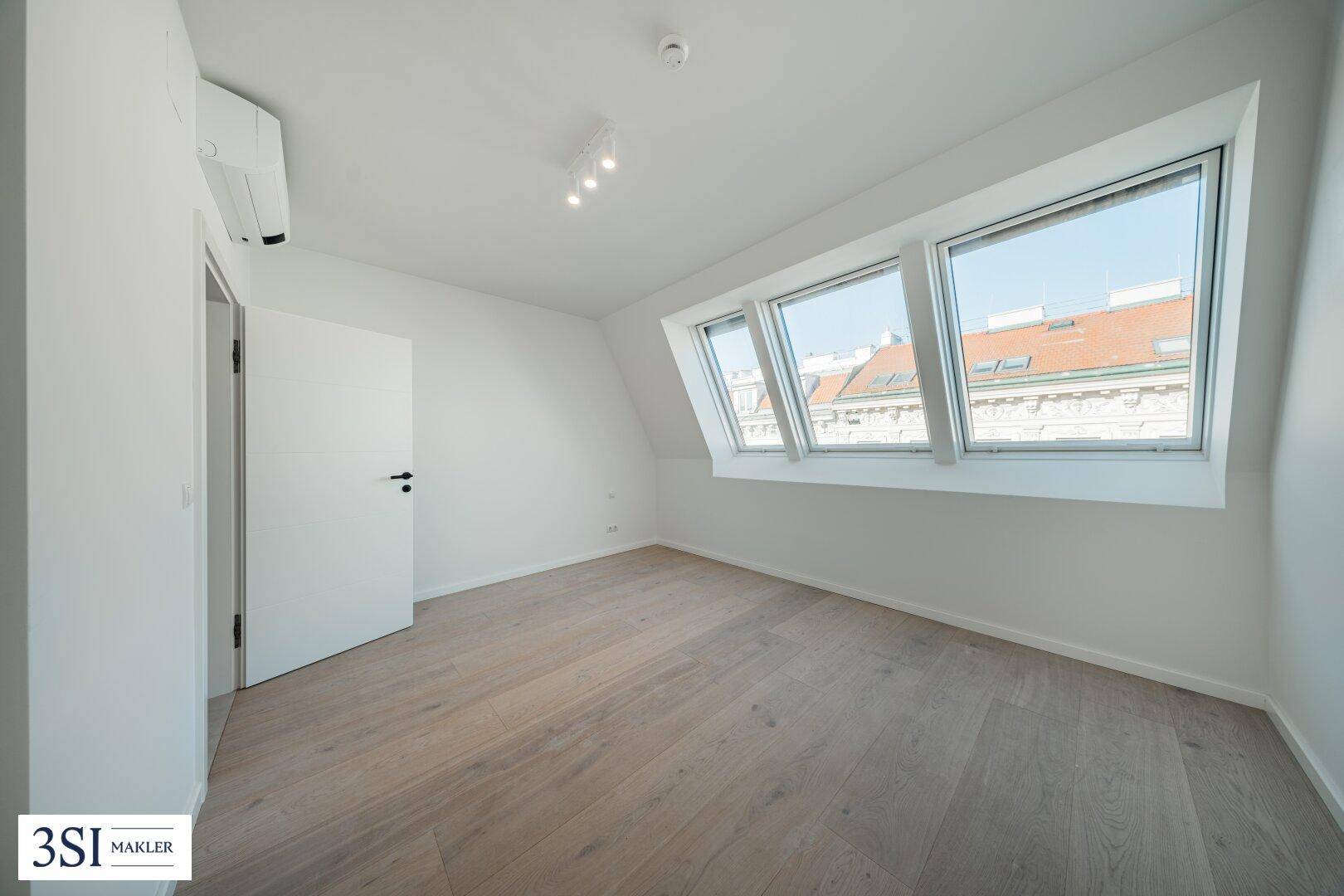 Modernes Schlafzimmer im Dachgeschoss mit Holzboden, Klimaanlage und schrägen Dachfenstern.
