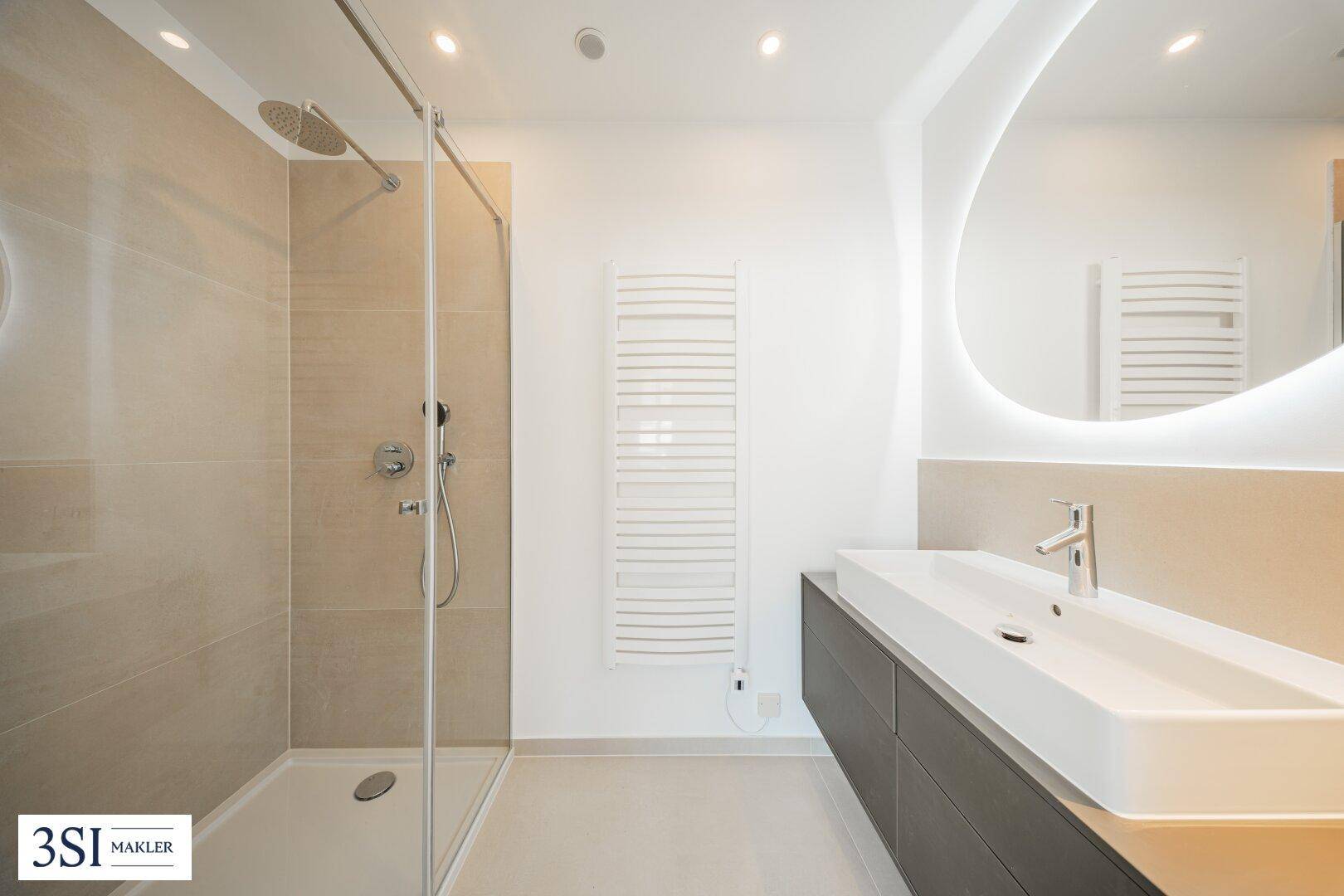 Modernes Badezimmer mit großer begehbarer Dusche, Einzelwaschbecken und beheiztem Handtuchhalter.