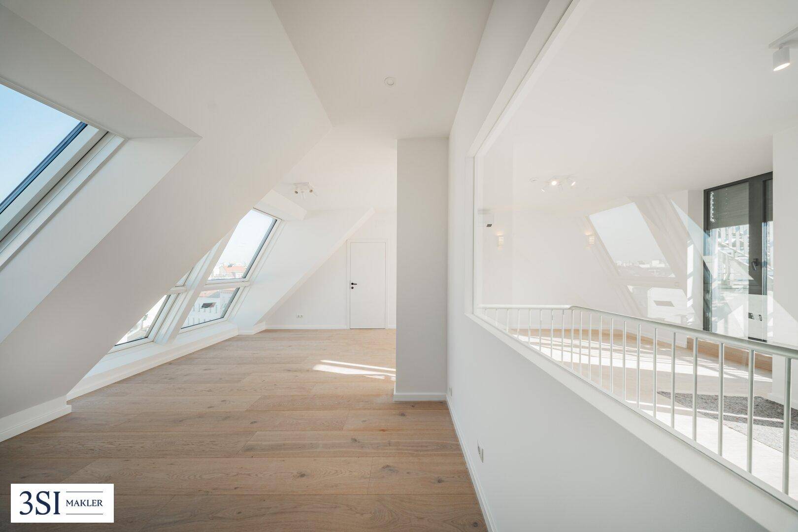 Helles, offenes Dachgeschosszimmer mit schrägen Wänden, großen Dachfenstern und Holzboden.