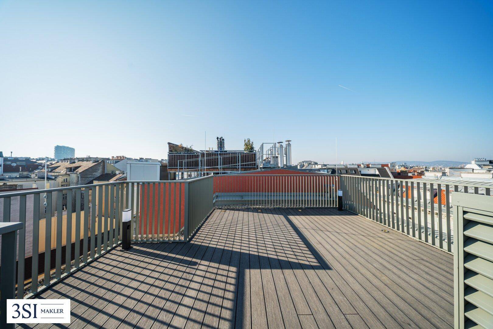 Weitläufige Dachterrasse mit Holzboden und Panoramablick über die Dächer der Stadt.