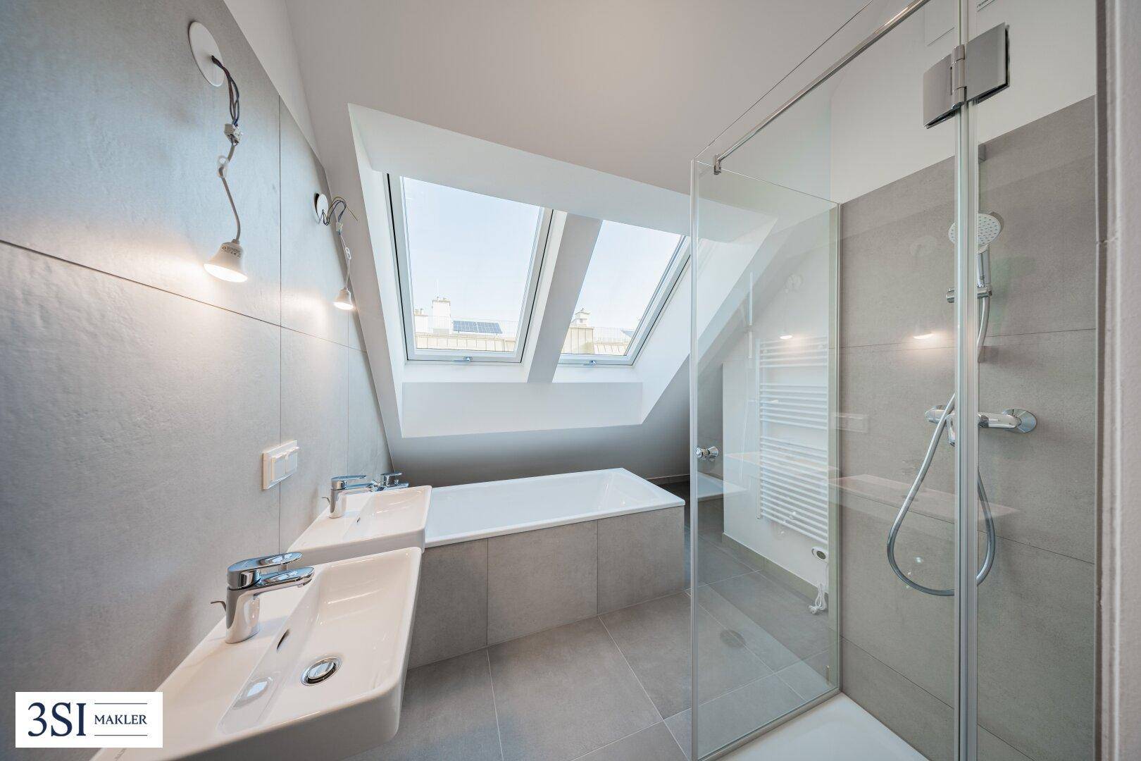Modernes Badezimmer im Dachgeschoss mit Doppelwaschbecken, Badewanne und Dusche.