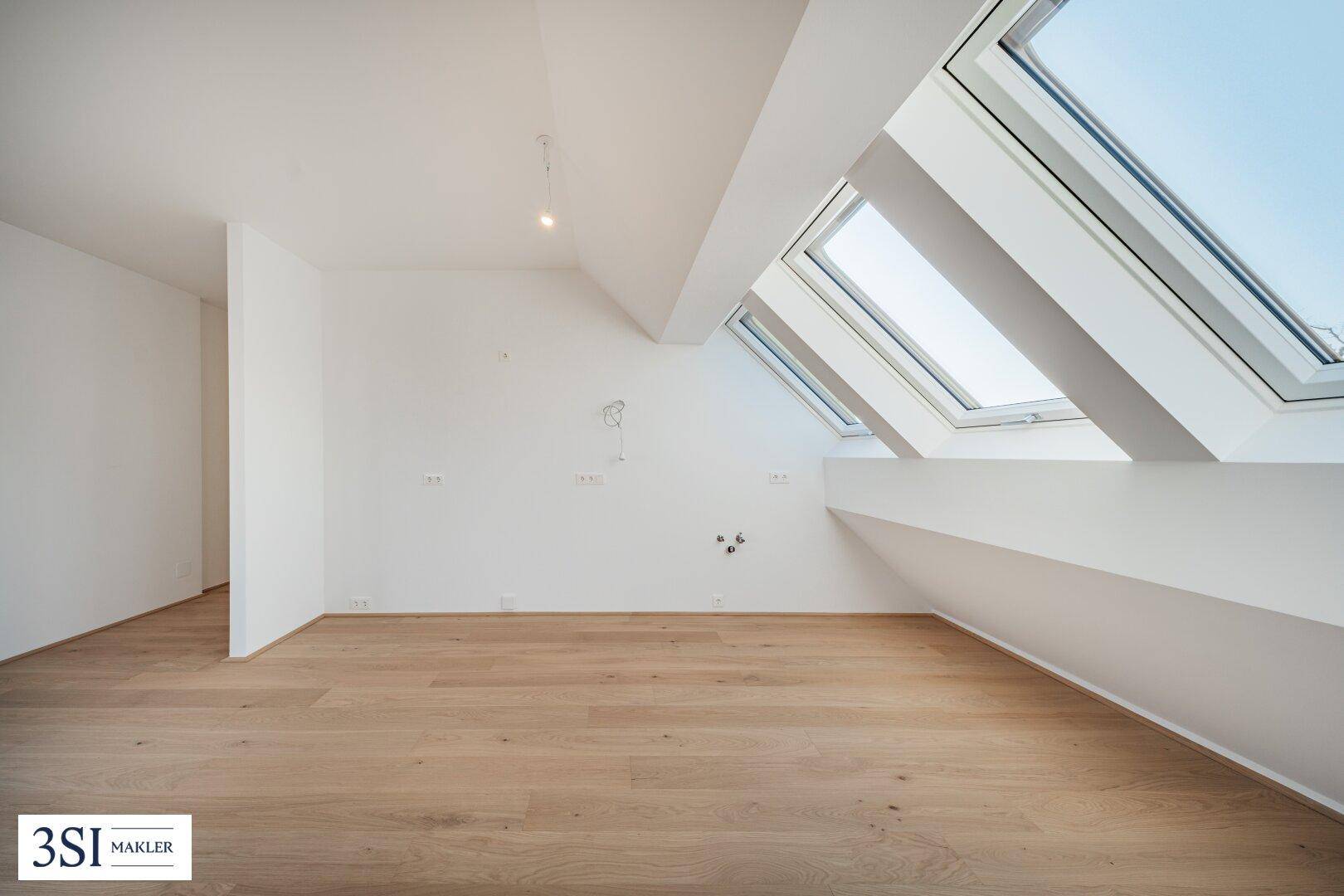 Großzügiger Dachgeschossraum mit Holzboden und mehreren schrägen Dachfenstern.