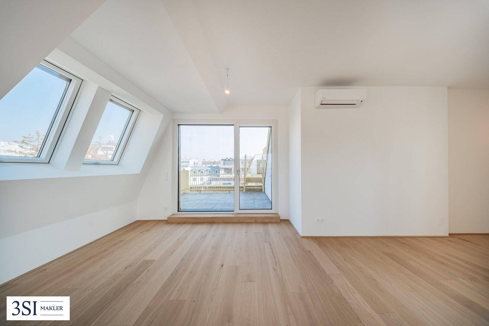 Heller Wohnbereich im Dachgeschoss mit Holzboden, Klimaanlage und Zugang zur Terrasse.
