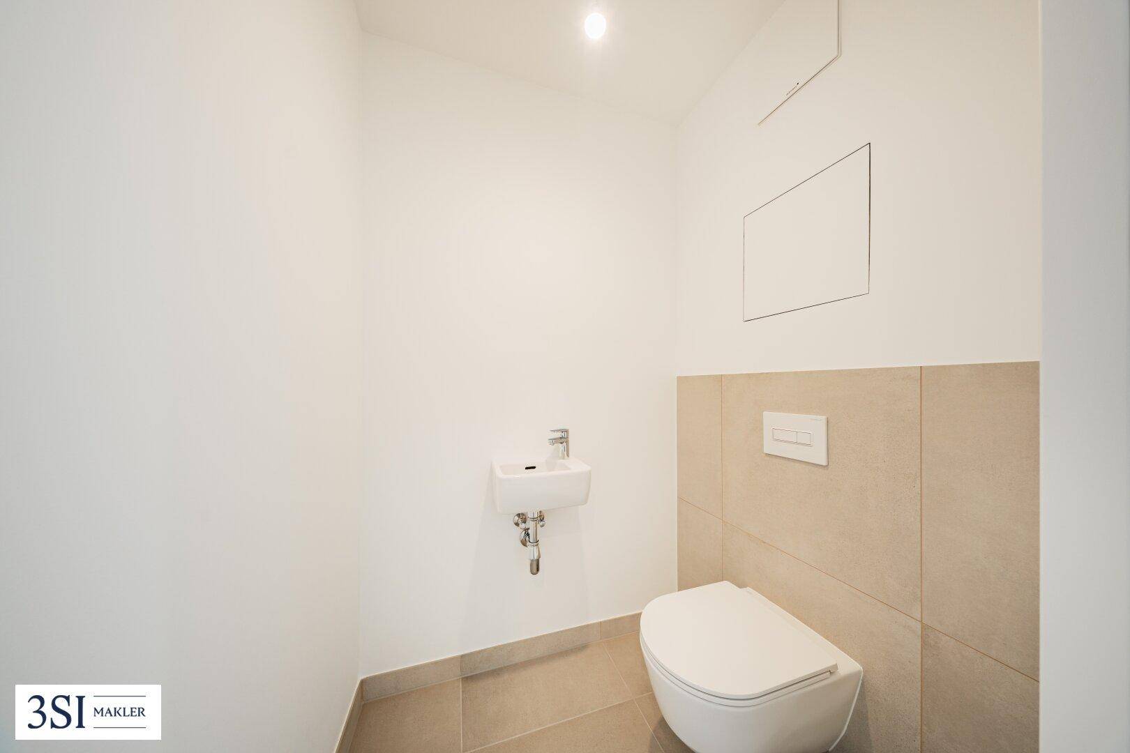 Modernes Gäste-WC mit Wand-WC, kleinem Waschbecken und hellen Fliesen.