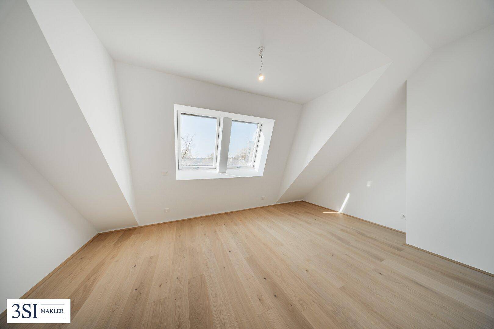 Helles Dachgeschosszimmer mit Holzboden und einem großen Dachfenster, ideal als Schlafzimmer.