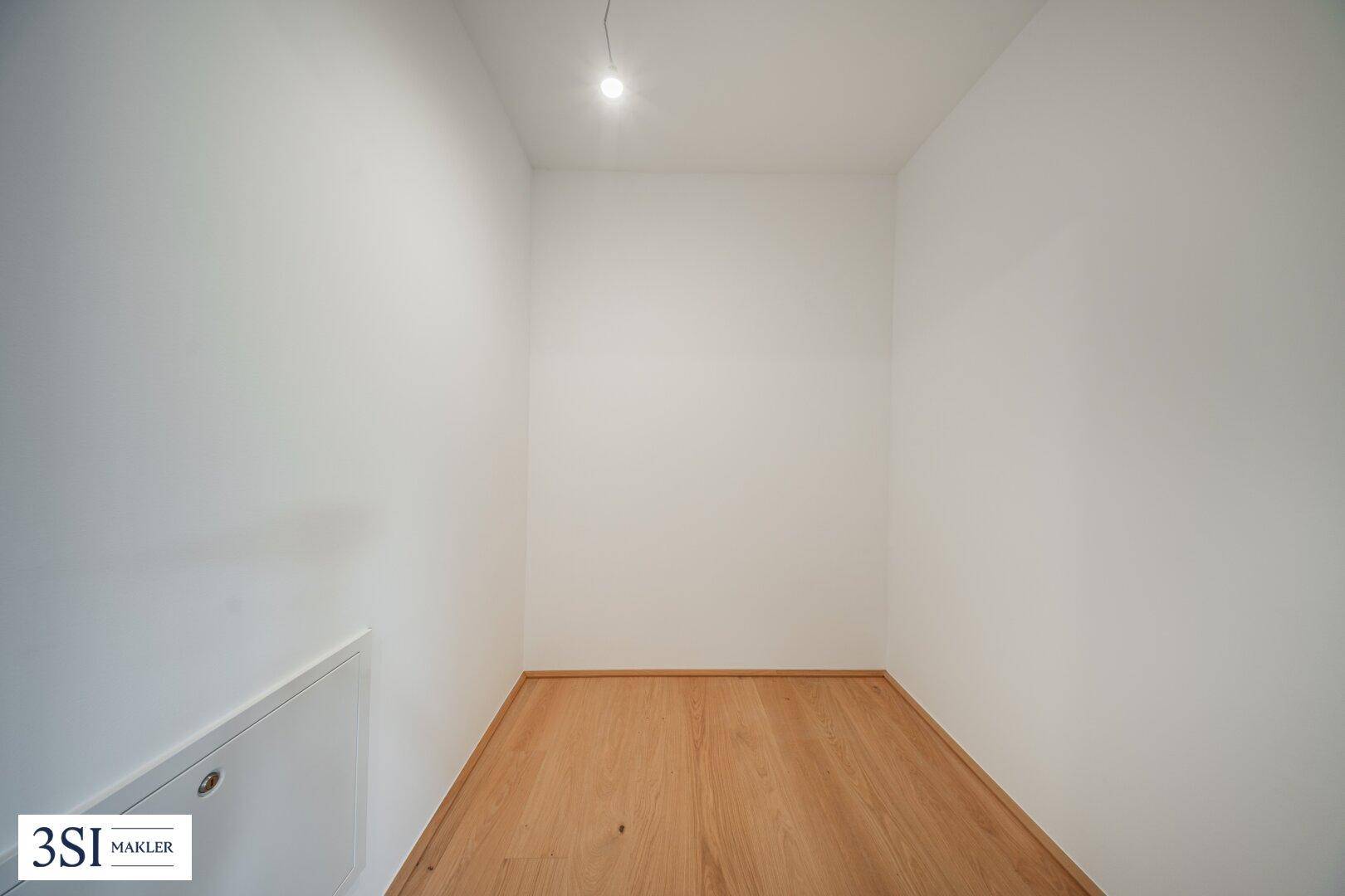 Kleiner, leerer Abstellraum mit Holzboden und weiß gestrichenen Wänden.