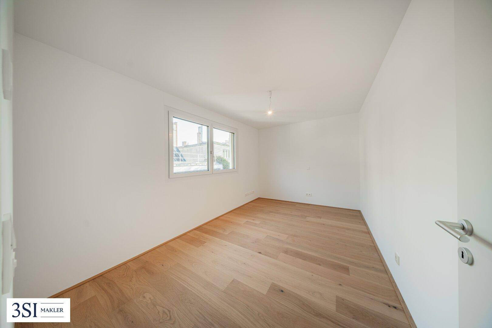 Helles Schlafzimmer mit Holzboden und Fenster, bereit zur Einrichtung.