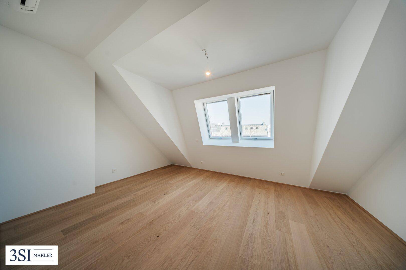 Helles Schlafzimmer mit Holzboden, schrägen Wänden und einem Fenster mit Stadtblick.