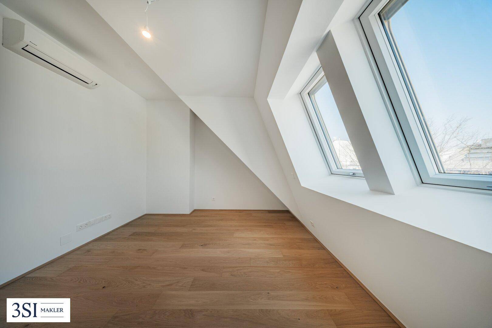 Lichtdurchflutetes Schlafzimmer mit Holzboden, Dachfenstern und Klimaanlage.