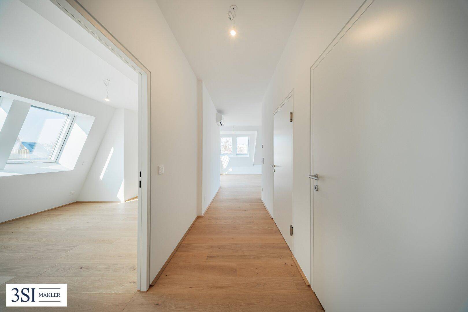 Heller Flur mit Holzboden und weißen Türen, der zu weiteren Räumen führt.