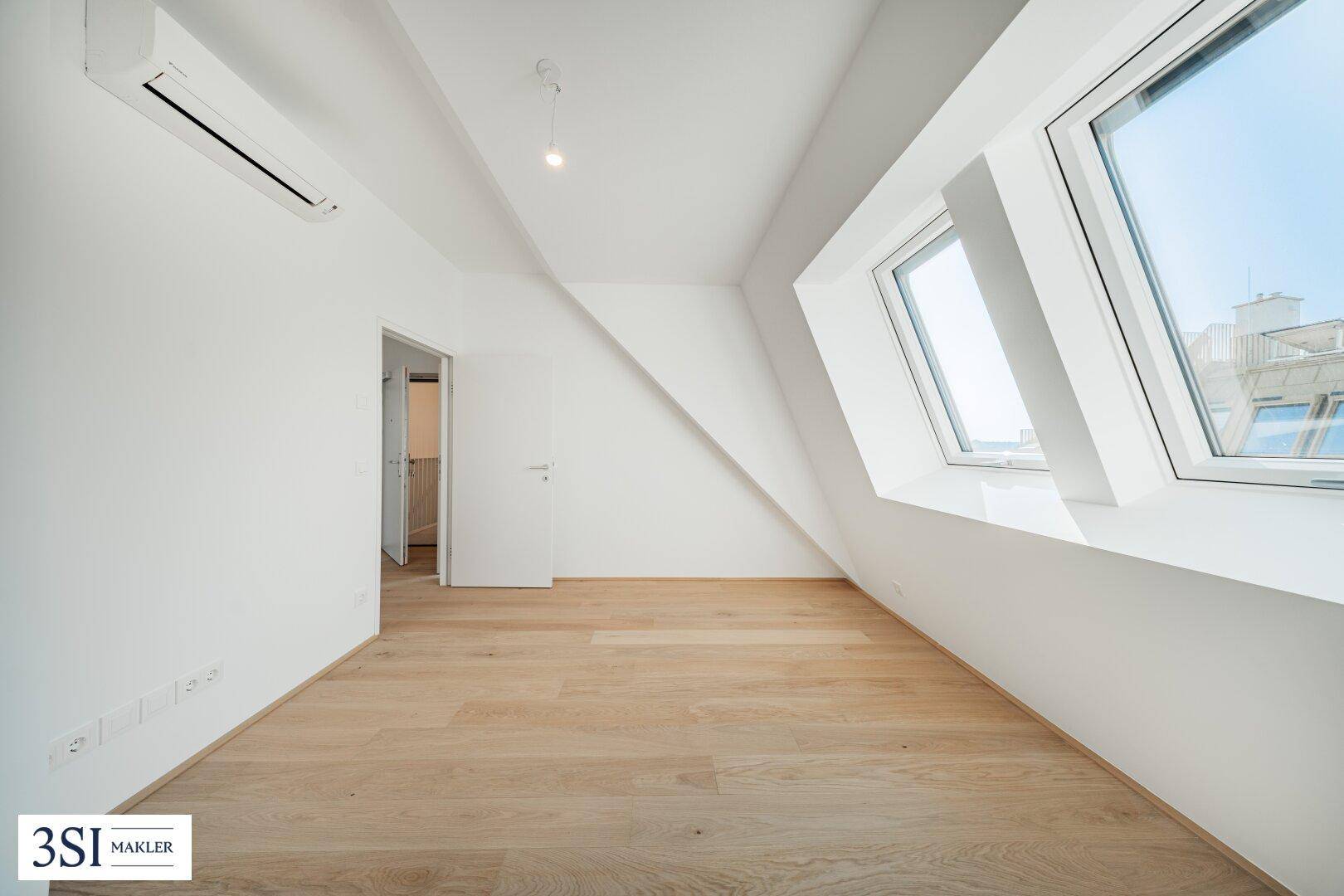 Lichtdurchflutetes Schlafzimmer mit Holzboden, Dachfenstern und Klimaanlage.