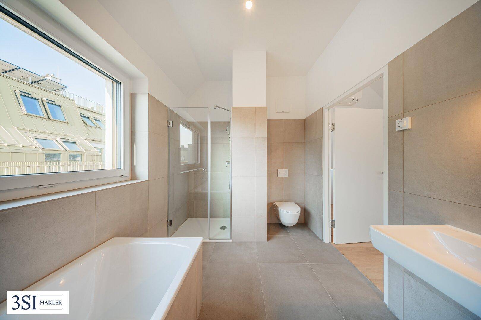 Geräumiges Badezimmer mit Badewanne, Duschkabine, wandhängendem WC und großem Fenster.