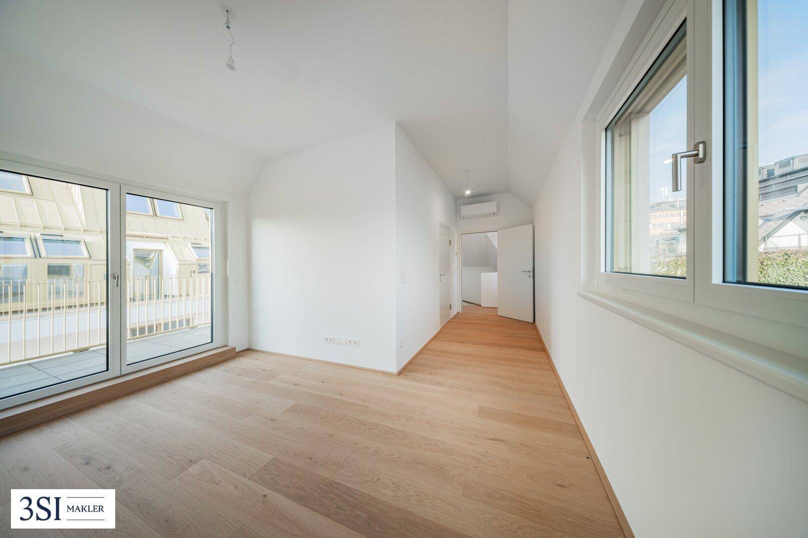 Lichtdurchflutetes Zimmer mit Holzboden und Zugang zu einem Balkon, ideal als Schlaf- oder Arbeitszimmer.