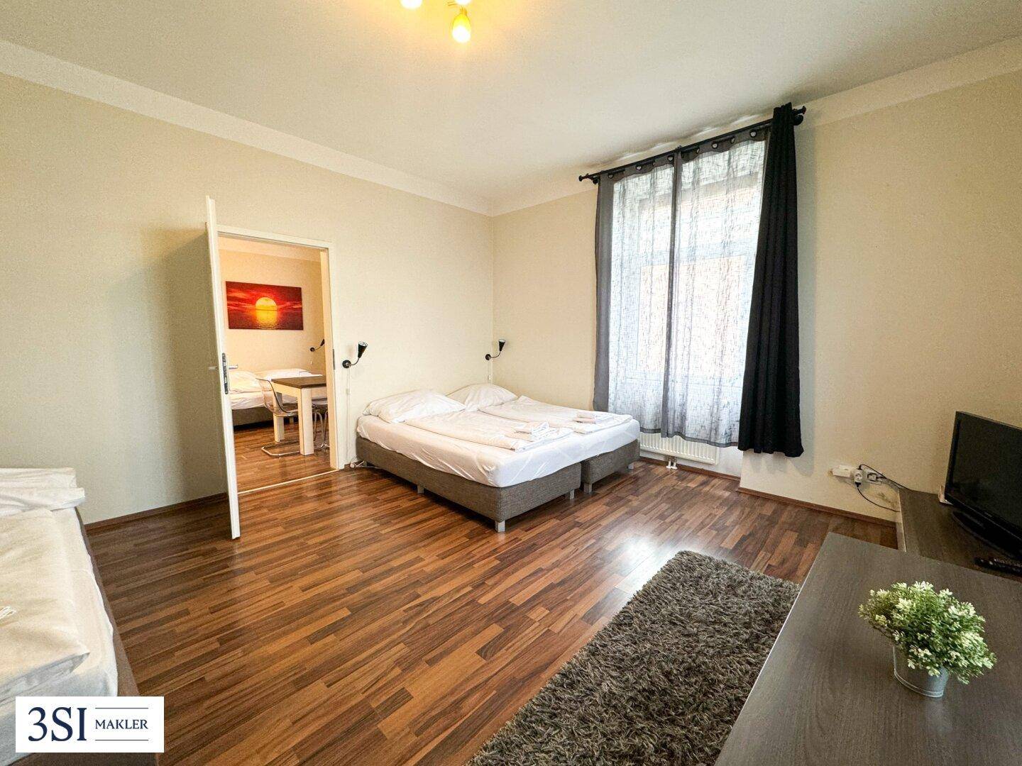 Helles Schlafzimmer mit Holzboden und Zugang zu einem weiteren Zimmer.