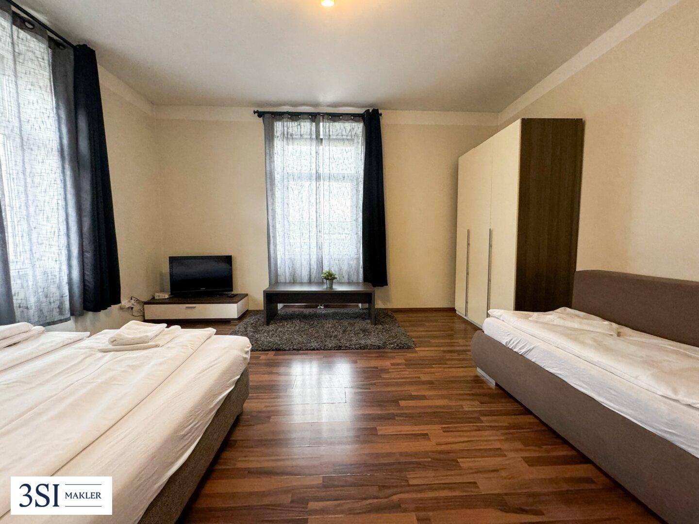 Geräumiges Schlafzimmer mit zwei Betten, Kleiderschrank und Holzboden.