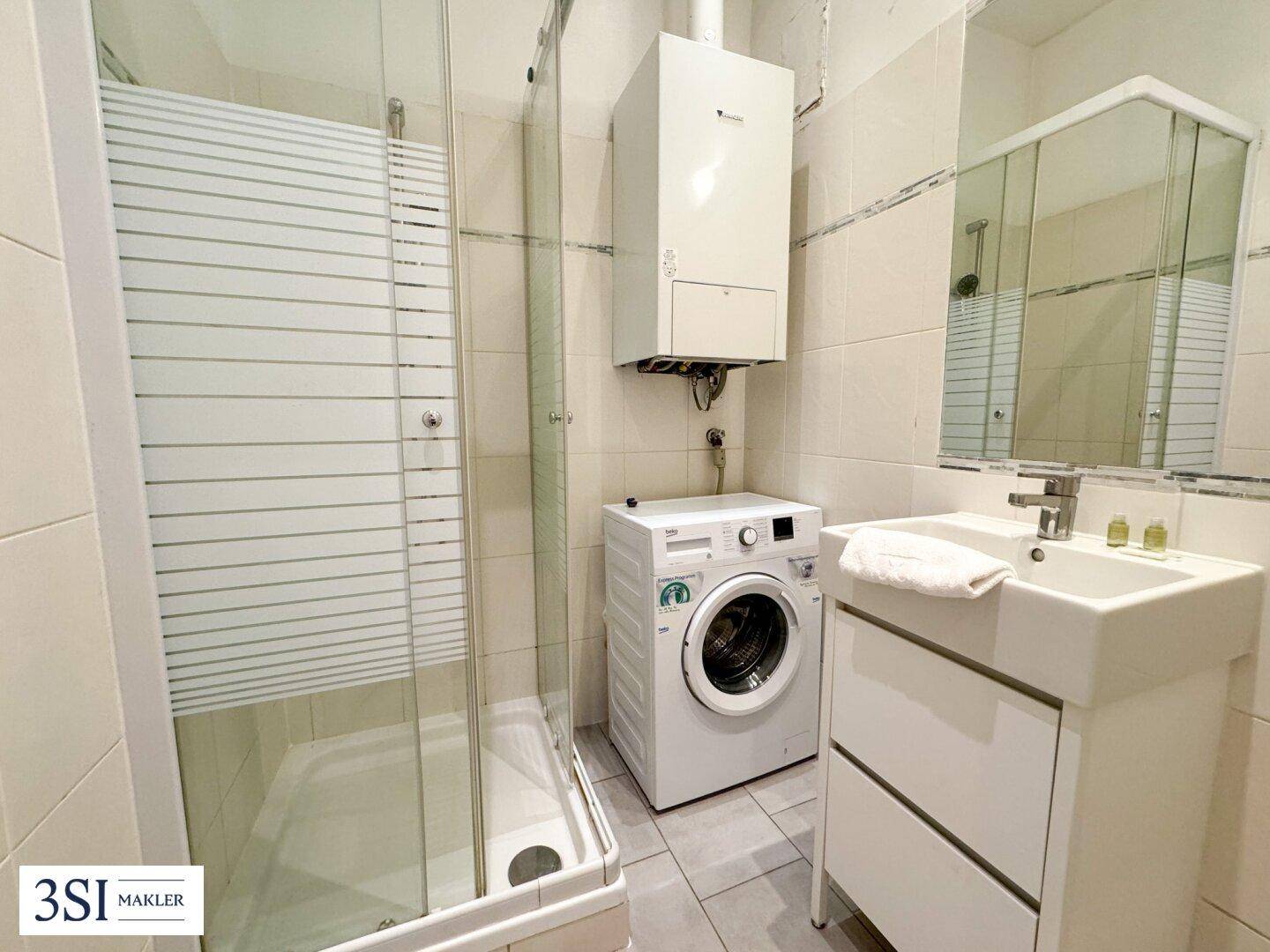 Funktionales Badezimmer mit Dusche, Waschbecken und Waschmaschine.
