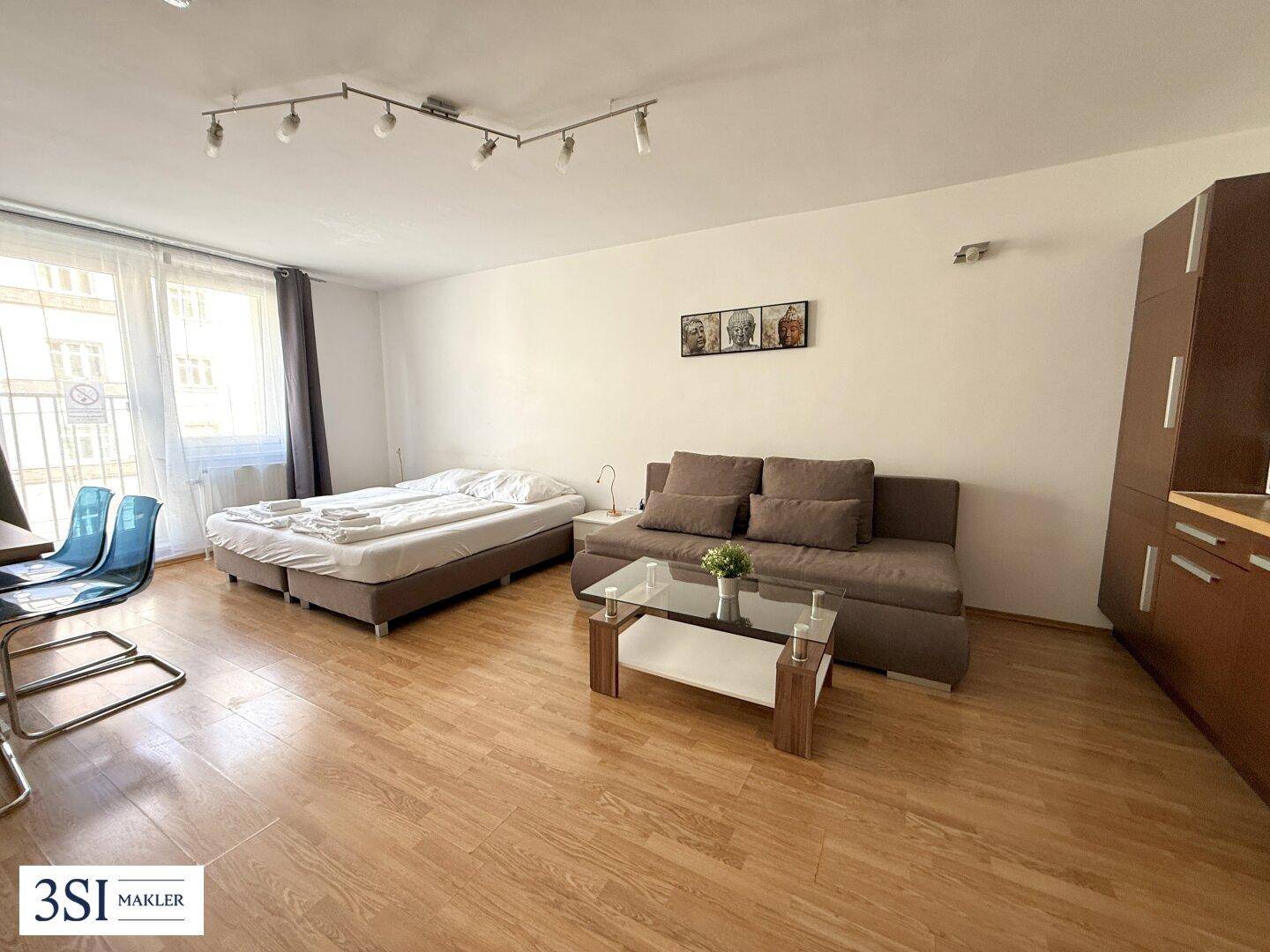 Heller Wohnraum mit großem Fenster, Schlafsofa und Esstisch, kombiniert mit einem Schlafbereich.