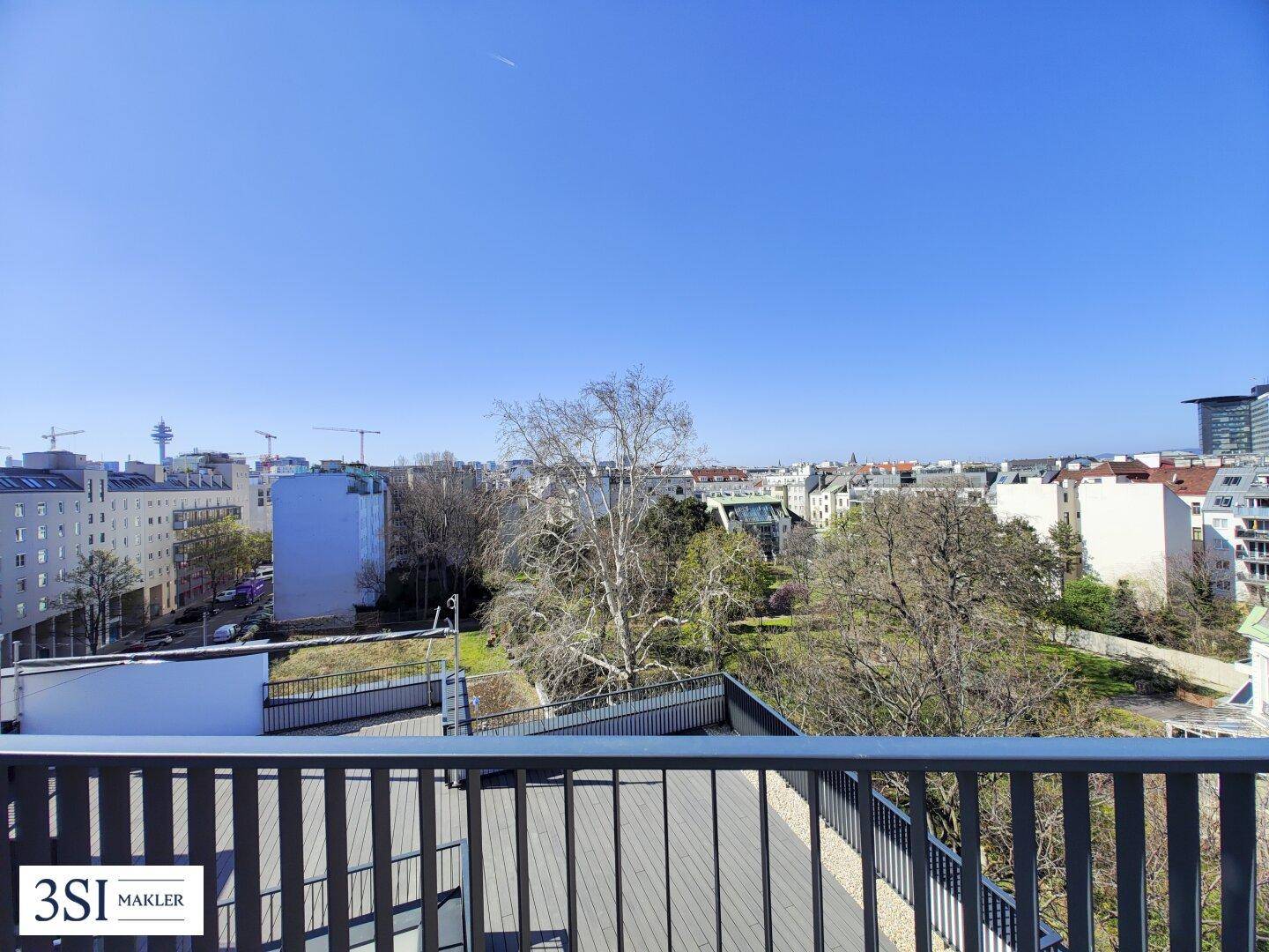 Dachterrasse mit Holzboden und weitem Blick auf eine grüne Parklandschaft und die Stadt.