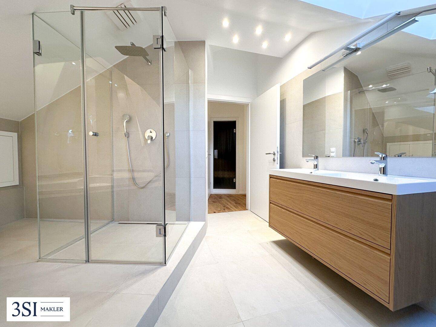 Modernes Badezimmer mit Doppelwaschbecken, großer Dusche und hellen Fliesen.