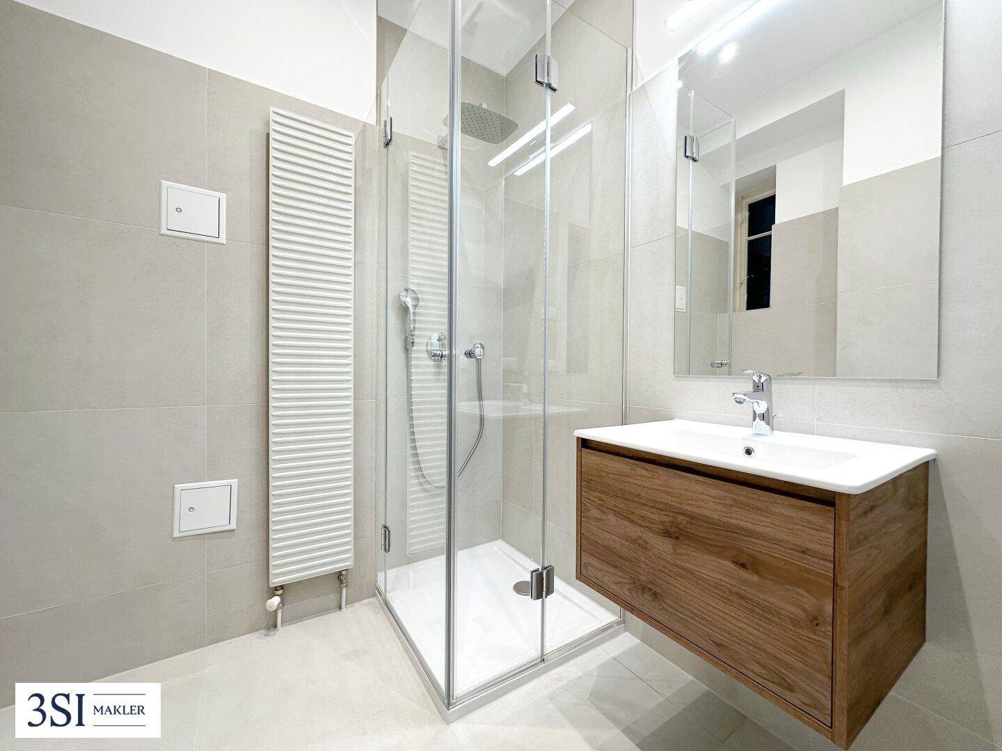 Helles Badezimmer mit Dusche, Einzelwaschbecken und beheiztem Handtuchhalter.