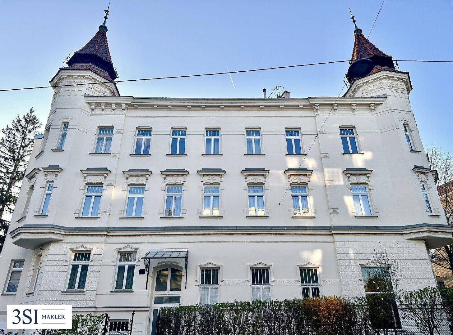Historisches Gebäude mit markanten Türmen und vielen Fenstern unter blauem Himmel.