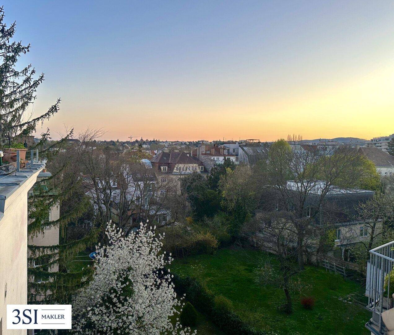 Weitläufiger Blick über grüne Gärten und die umliegende Nachbarschaft bei Sonnenuntergang.