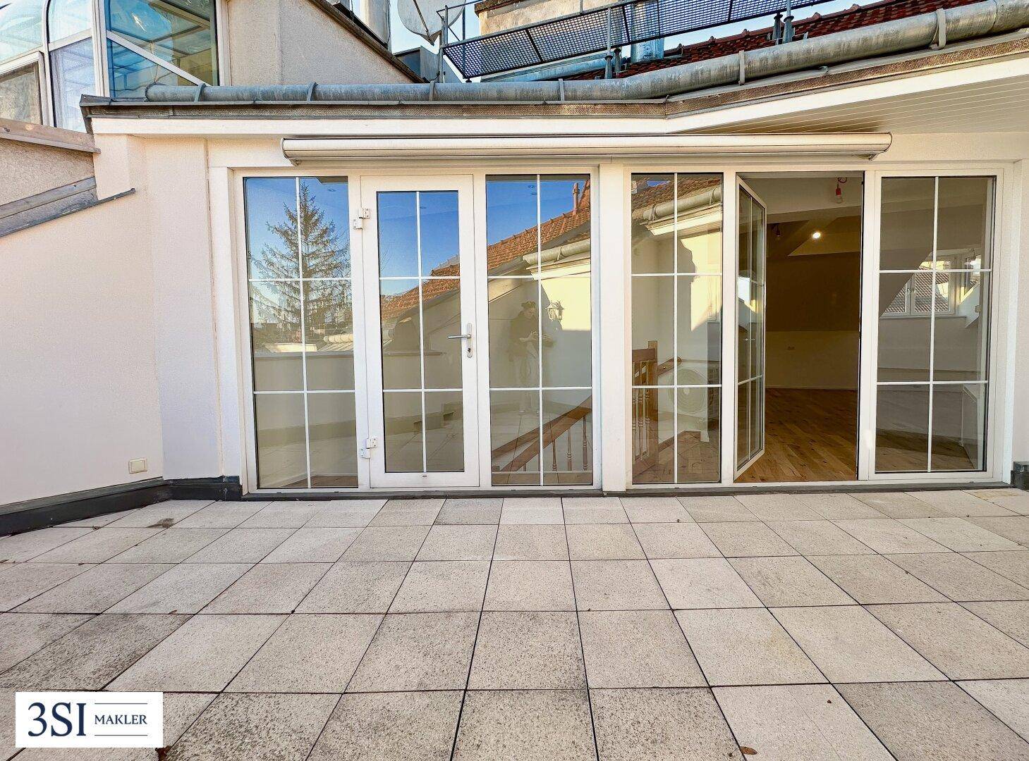 Große, geflieste Terrasse mit Zugang zum Innenbereich und Blick auf die Umgebung.