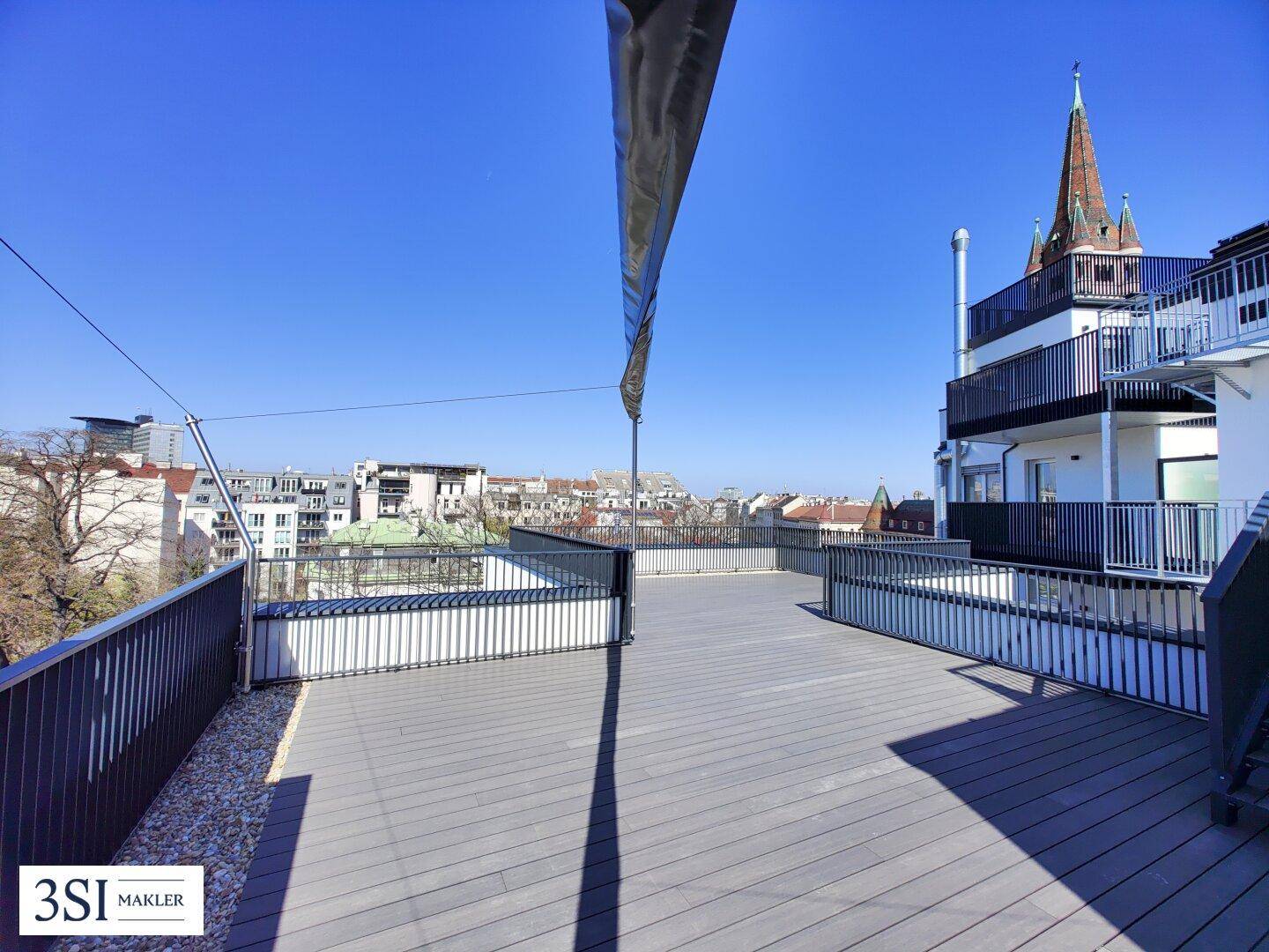 Geräumige Dachterrasse mit Holzdeck und weitem Blick über die Stadt und die Umgebung.