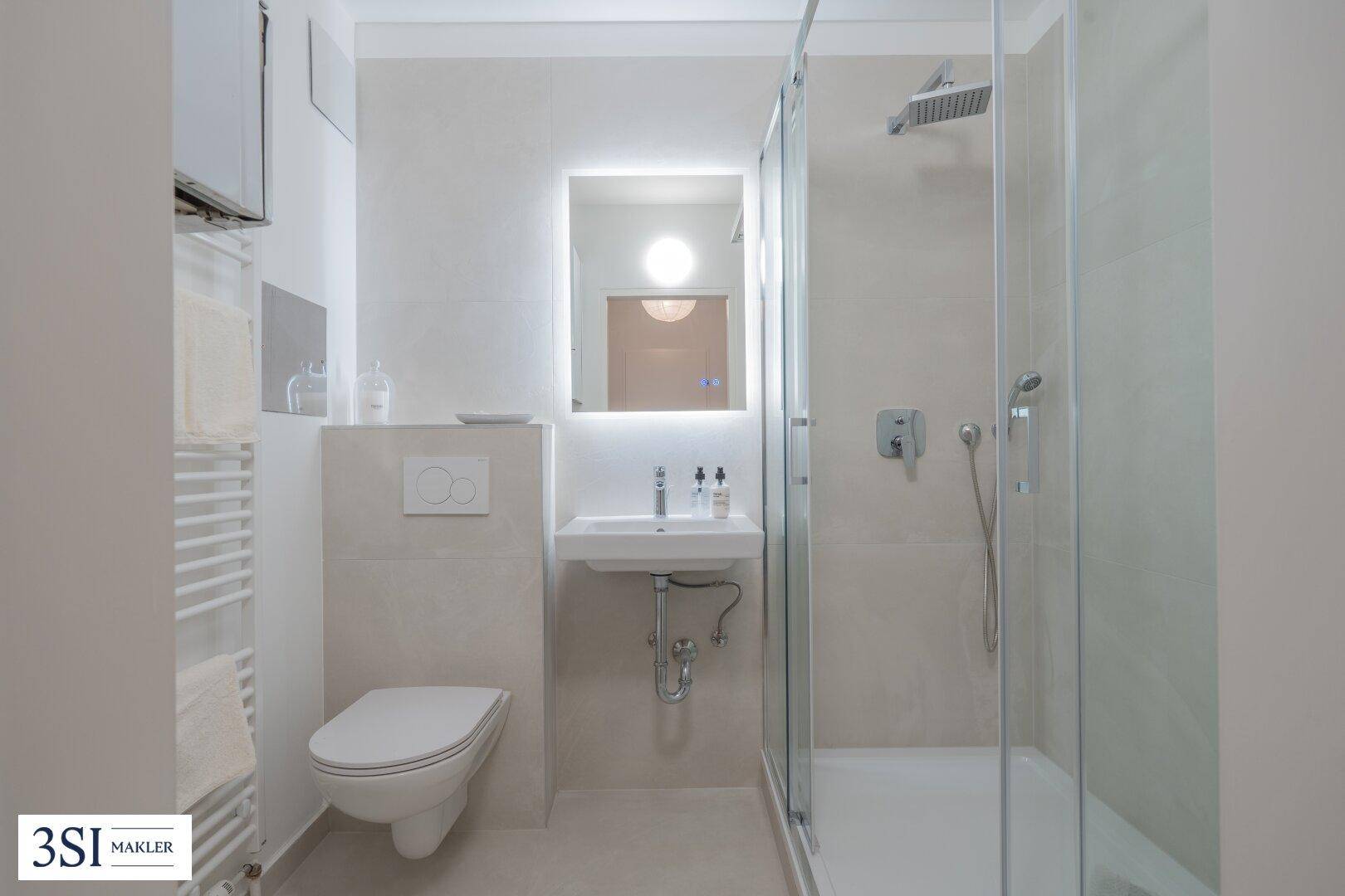 Modernes Badezimmer mit Dusche, wandhängendem WC und beheiztem Handtuchhalter.