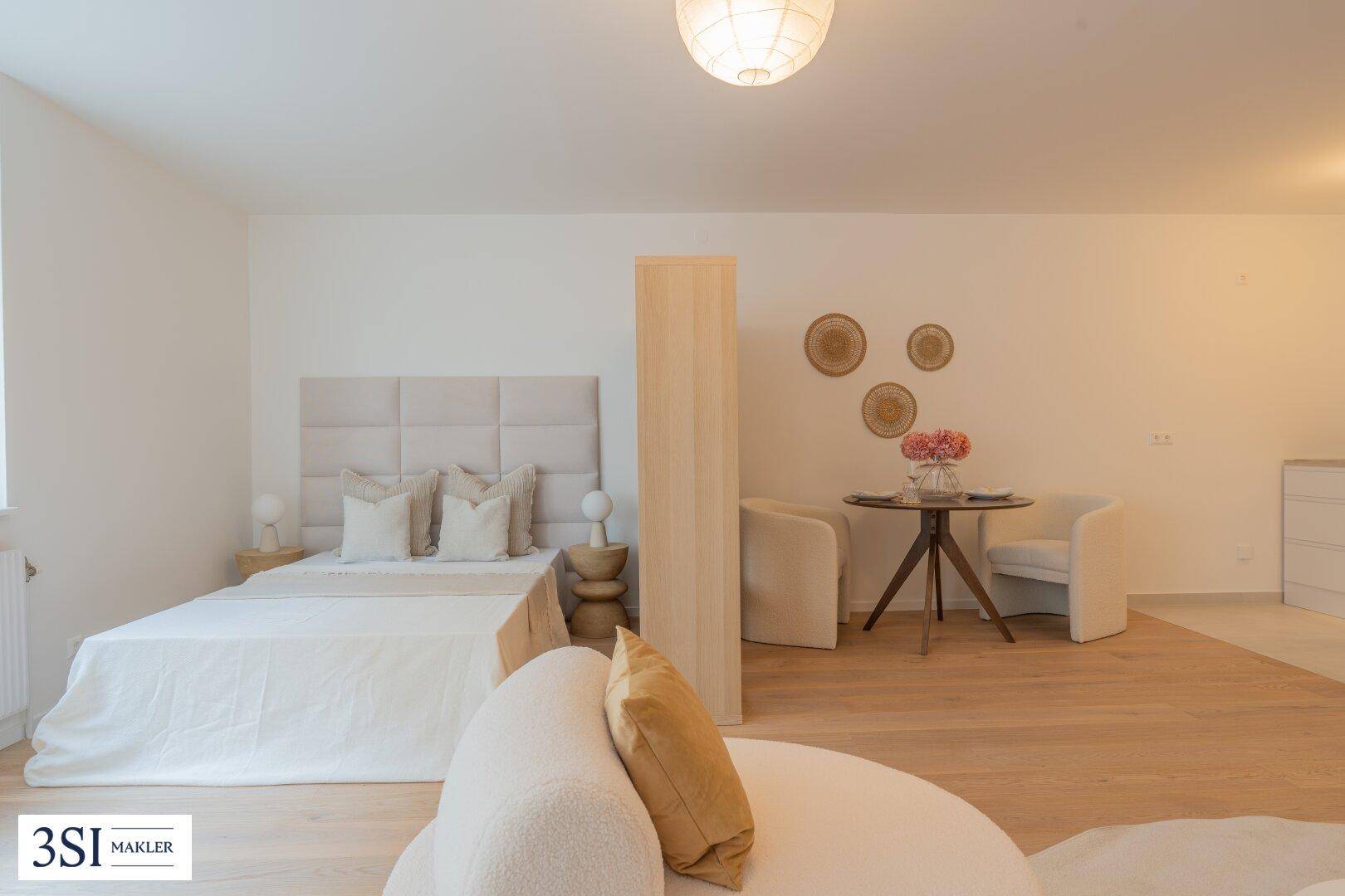 Gemütliches Schlafzimmer mit großem Bett, Holzboden und kleiner Sitzecke.