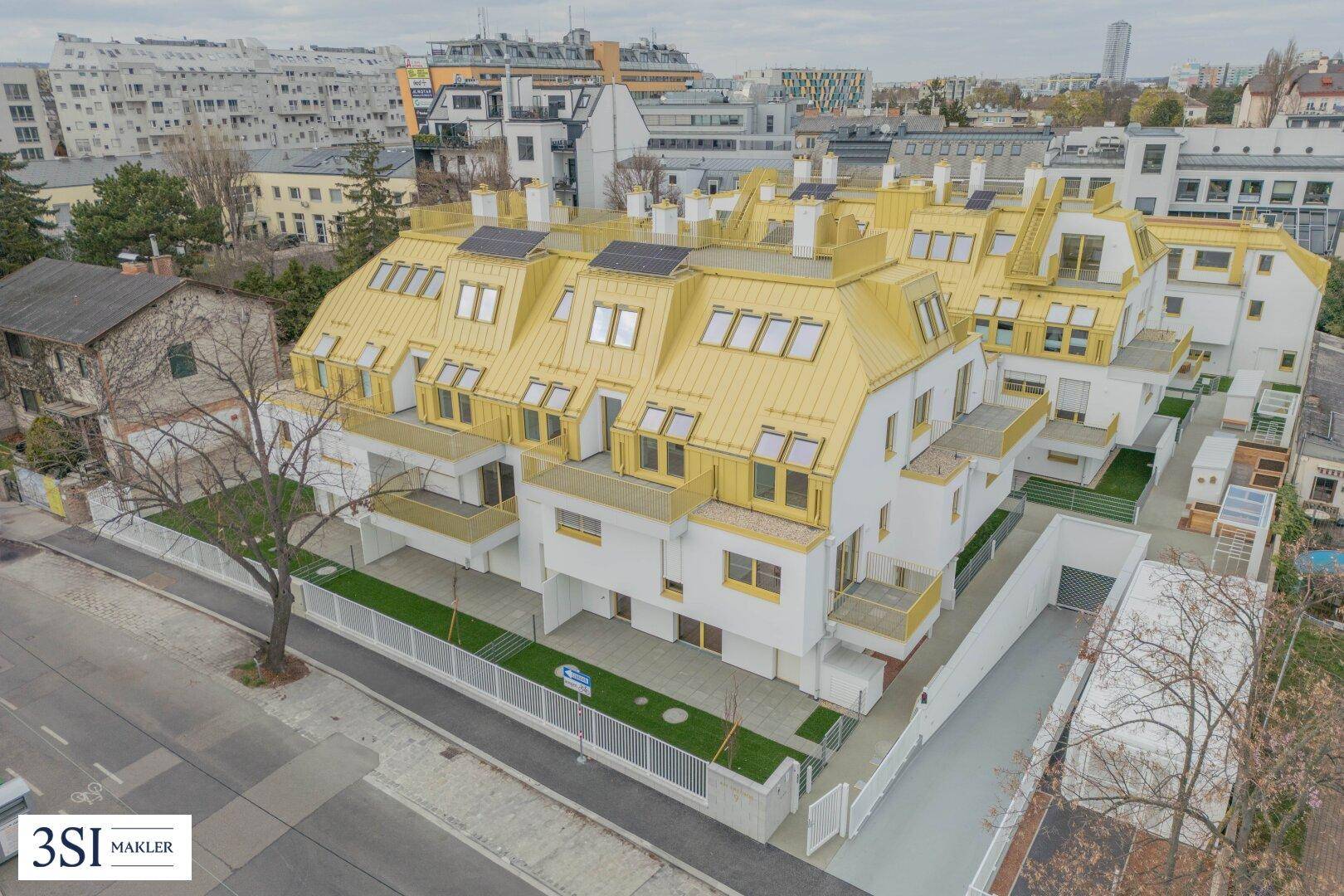 Luftaufnahme eines modernen Wohnkomplexes mit gelben Dächern und Balkonen in städtischer Umgebung.