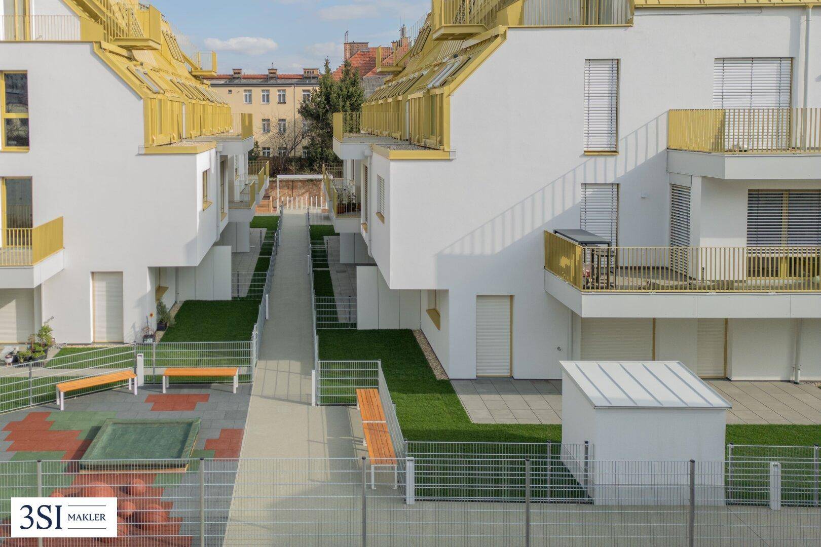 Gemeinschaftlicher Außenbereich zwischen den Gebäuden mit Spielplatz, Bänken und Grünflächen.