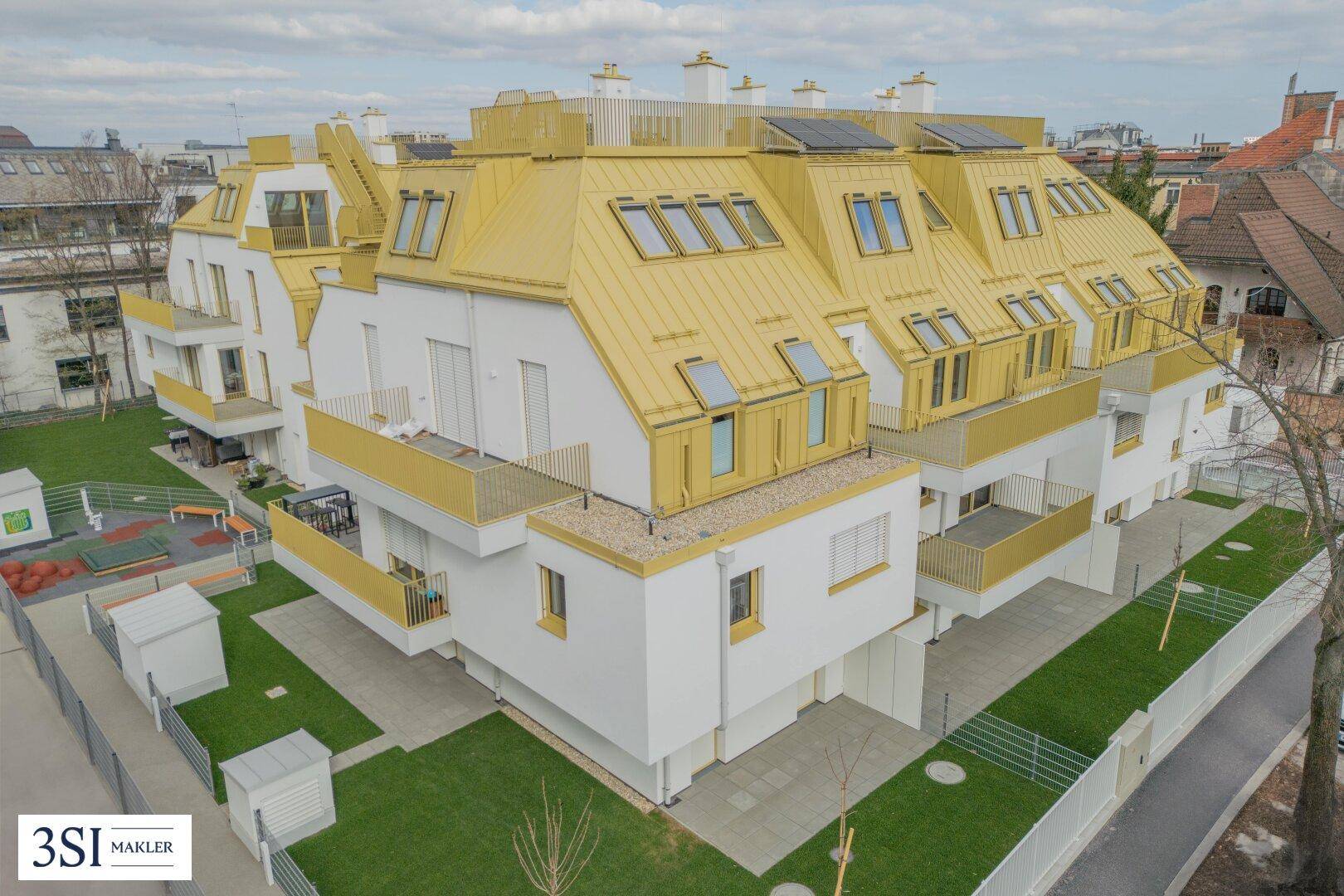 Gesamtansicht des modernen Wohnkomplexes von oben mit gelben Dächern und umliegenden Grünflächen.