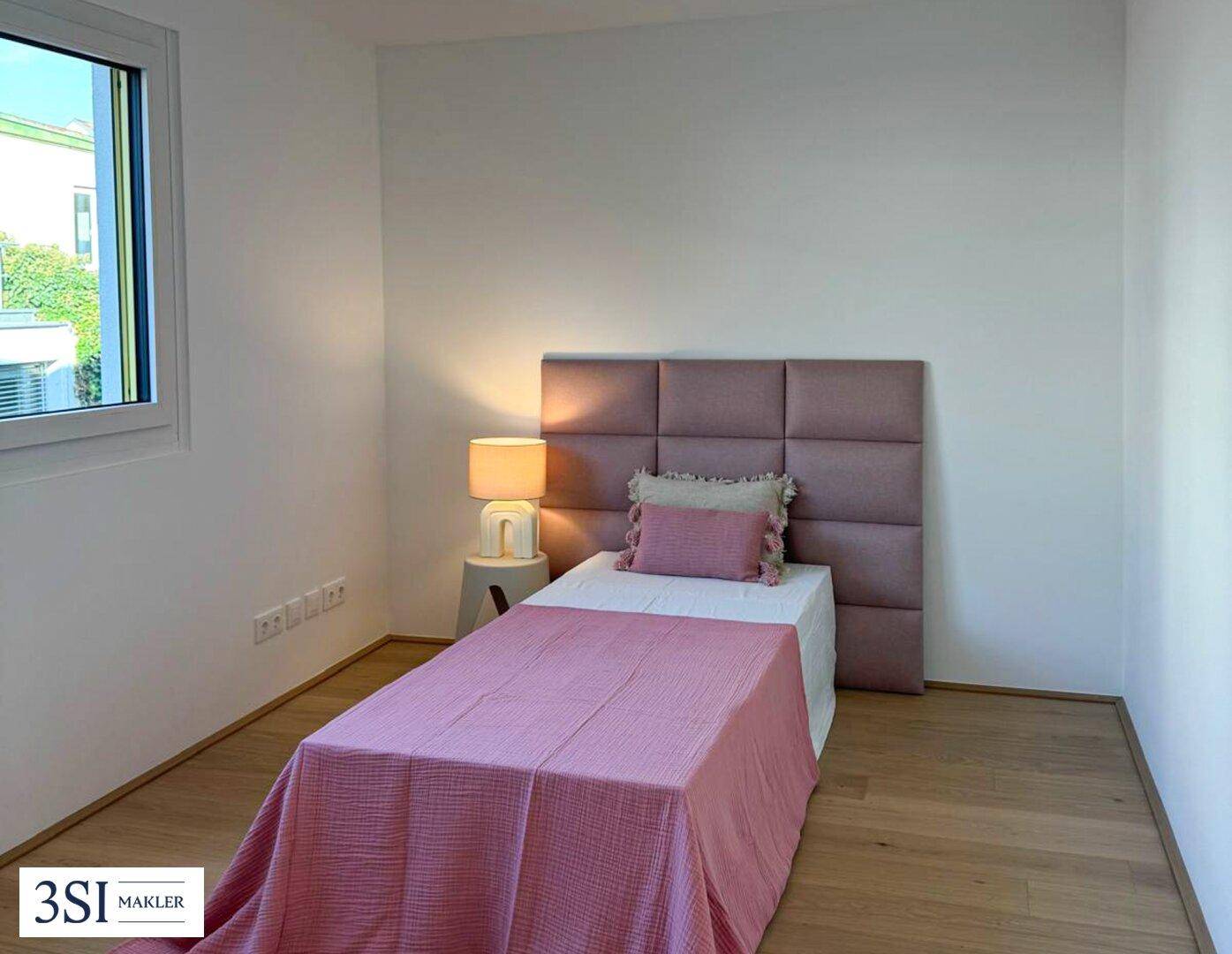 Kinderzimmer oder Gästezimmer mit Einzelbett, rosa Bettwäsche und hellem Holzboden.