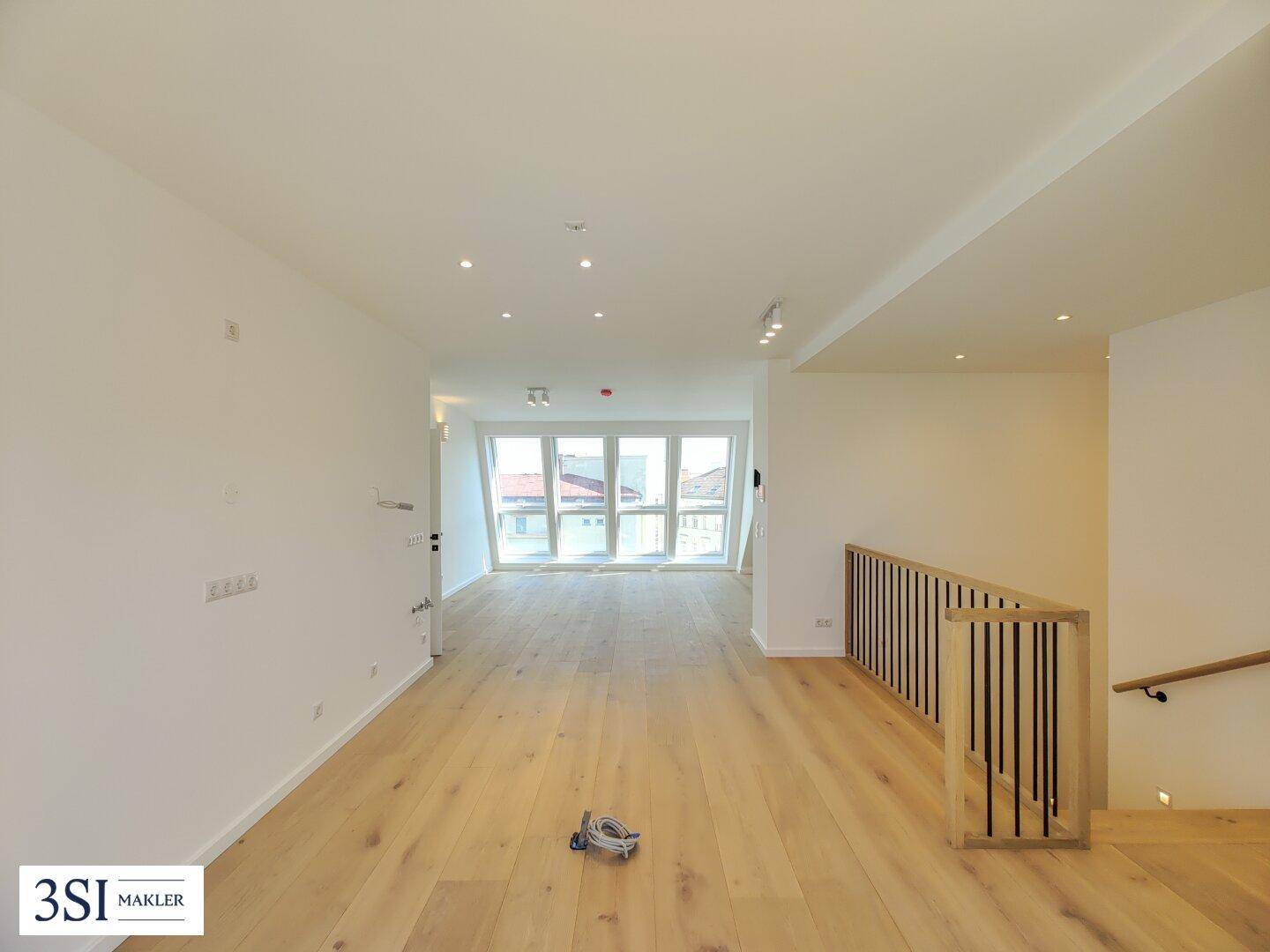 Heller, offener Wohnbereich mit Eichenparkett und moderner Holztreppe in einem Neubau.